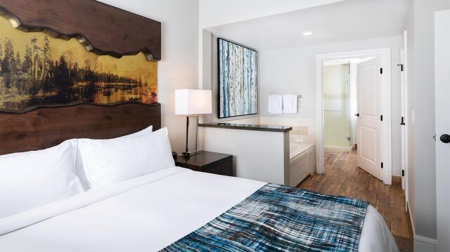 Bright modern bedroom with spa-like bath access and rustic wood accents