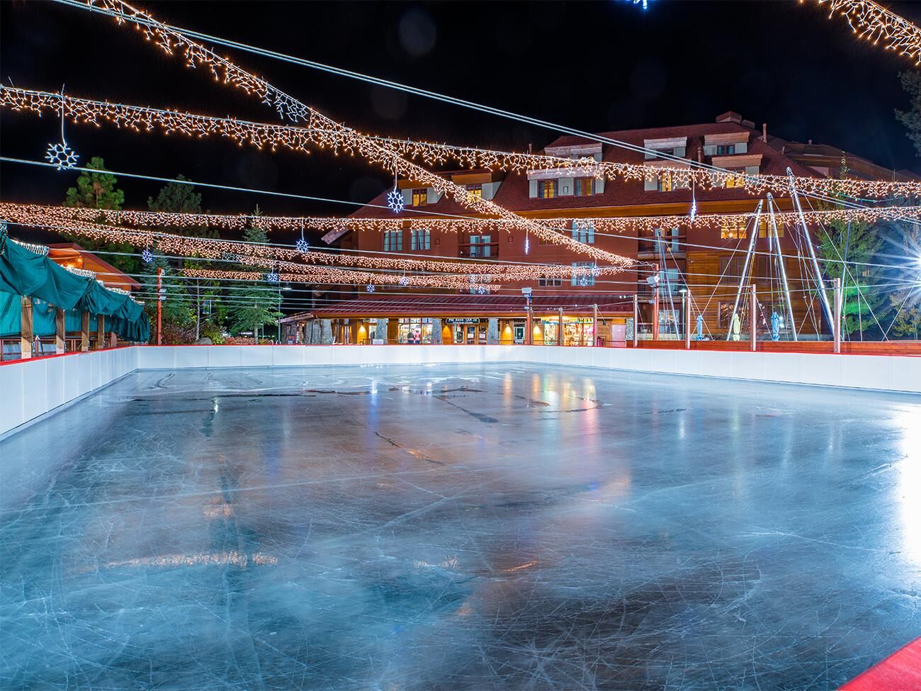Festive outdoor ice rink with twinkling lights and cozy lodge backdrop