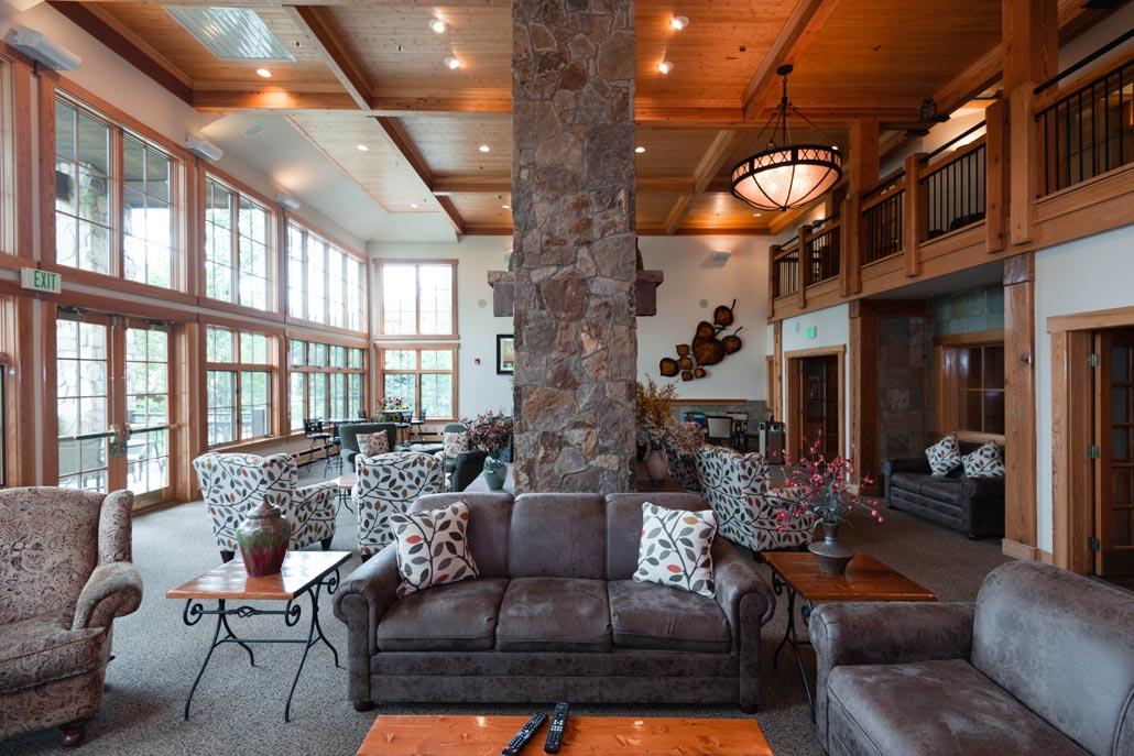 Spacious lodge lounge with stone fireplace, soaring ceilings, and bright windows