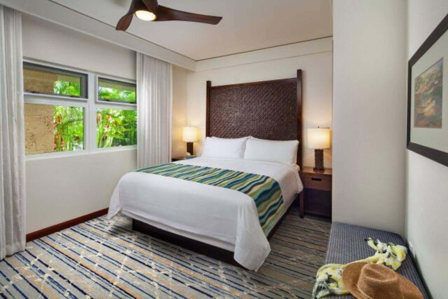 Bright tropical bedroom with plush bed, natural light, and serene garden views
