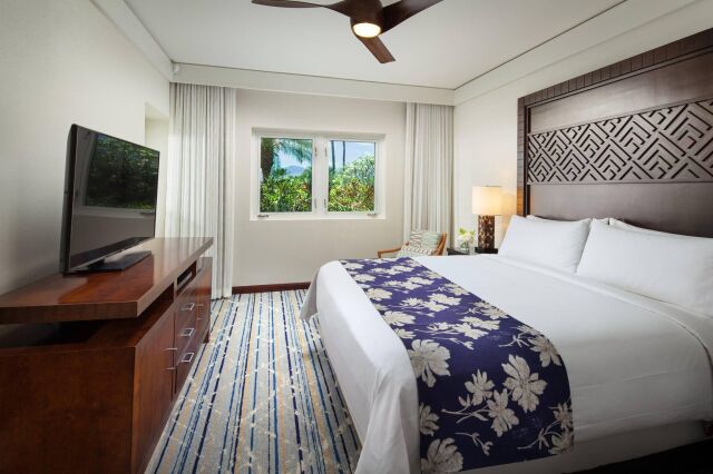 Bright tropical king bedroom with TV, ceiling fan, and garden views