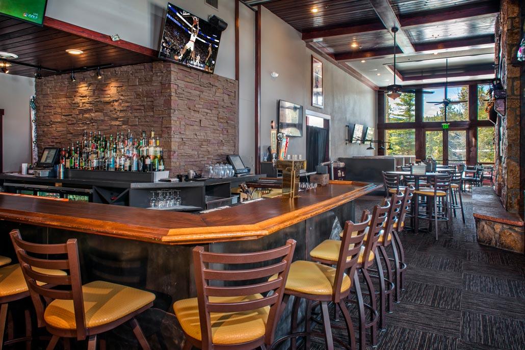 Upscale bar lounge with TVs, stone accents, and bright natural light