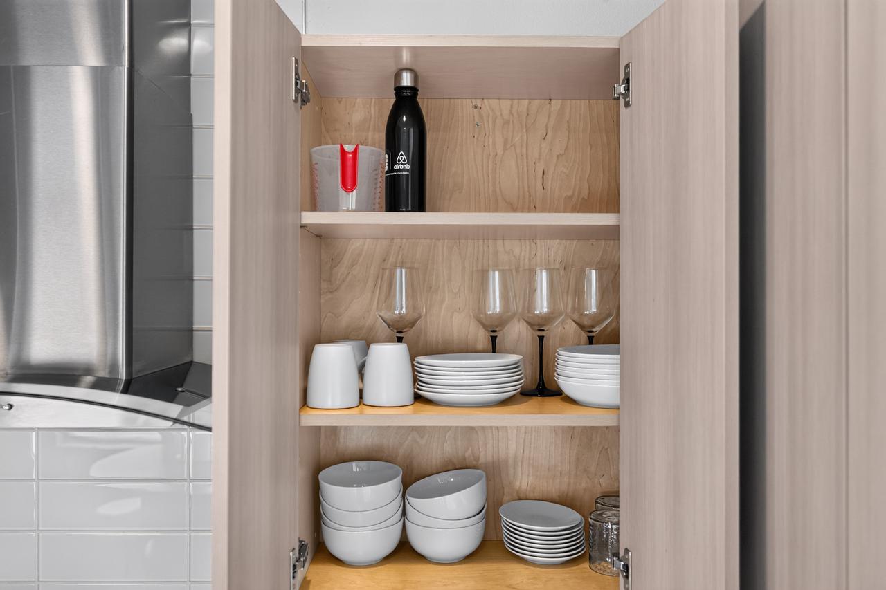 Well-stocked kitchen cabinet with dishes, glassware, and dining essentials