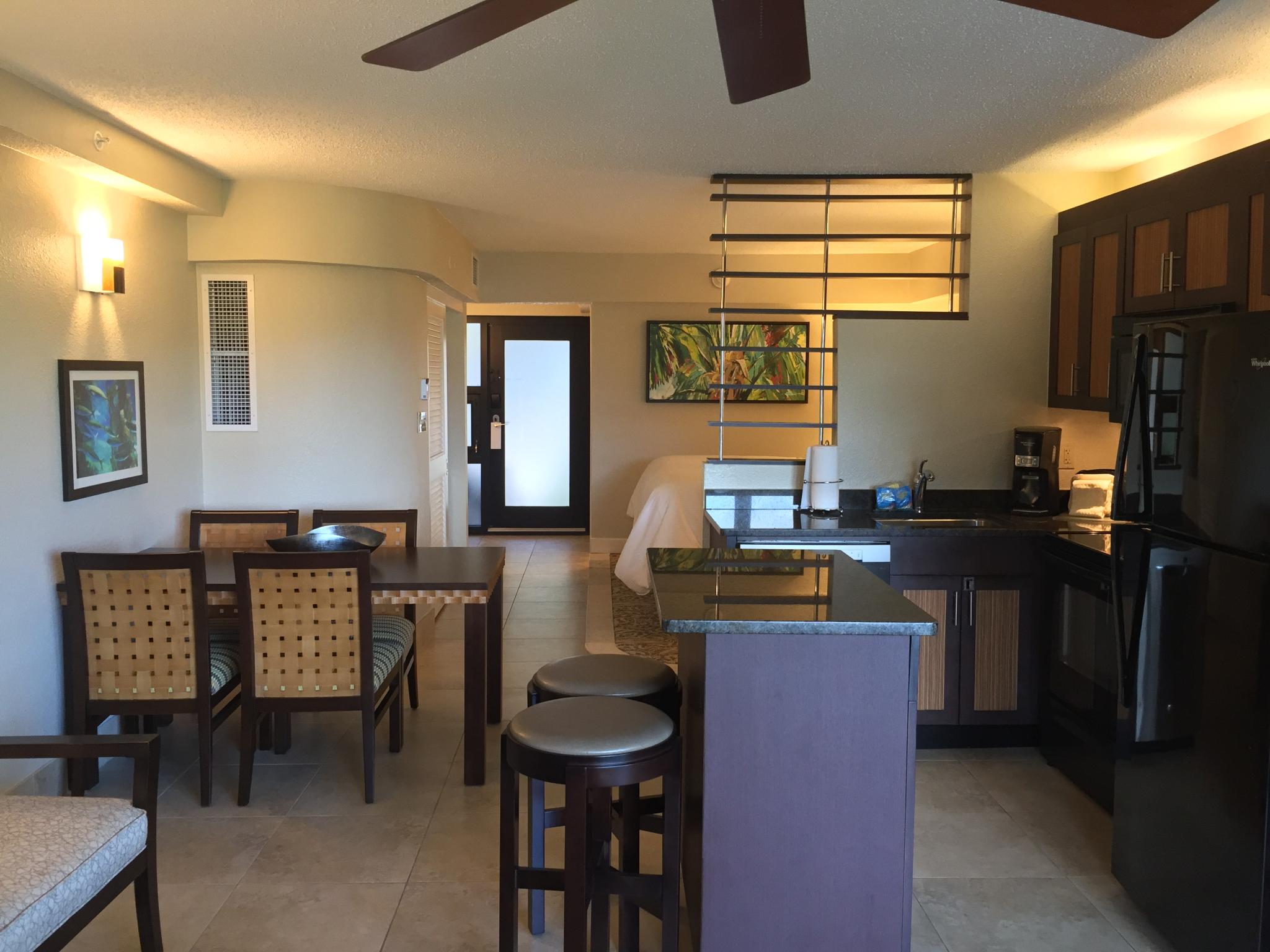 Modern studio with full kitchen, dining table, and sleek island seating