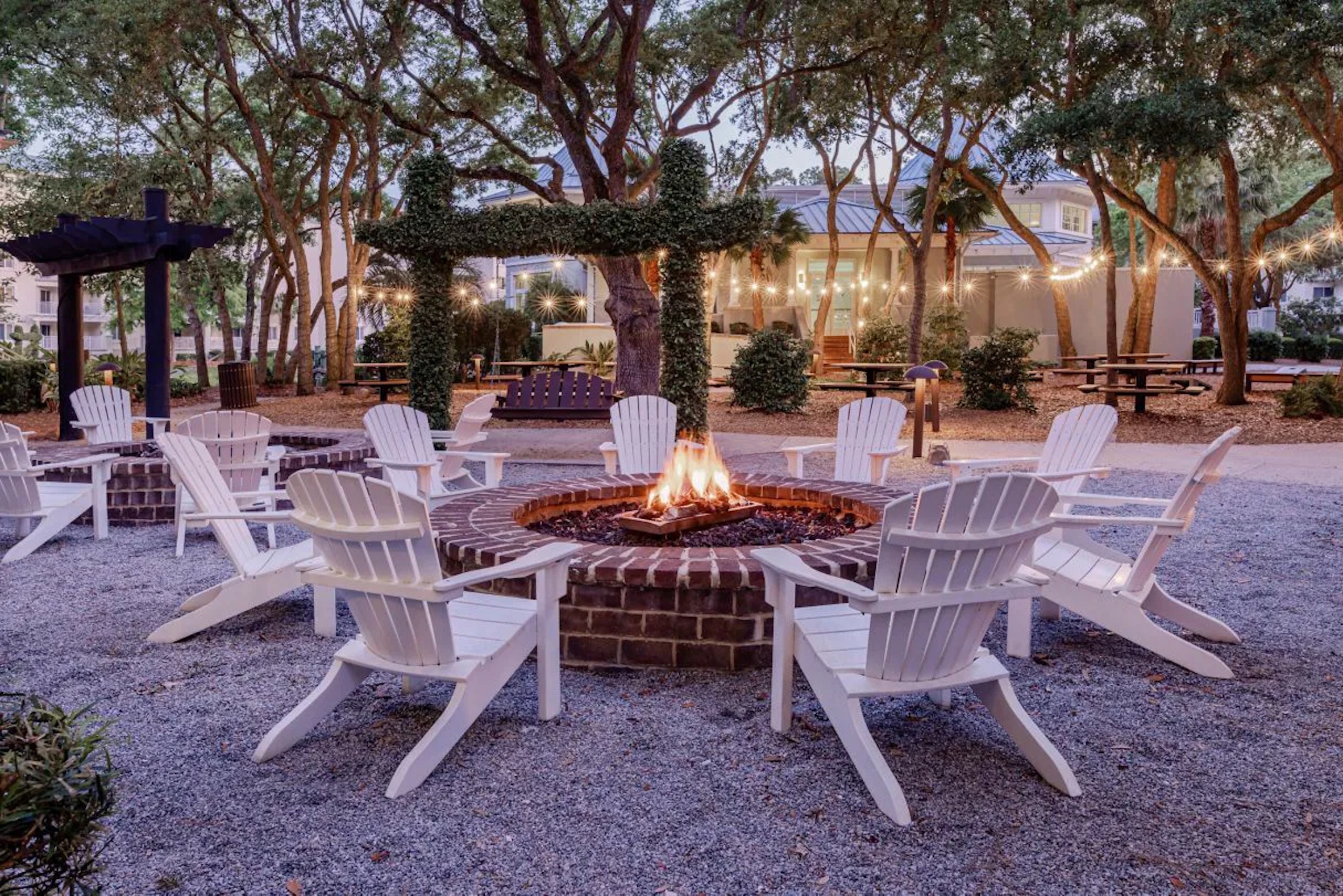 Cozy fire pit lounge with Adirondack chairs under glowing string lights