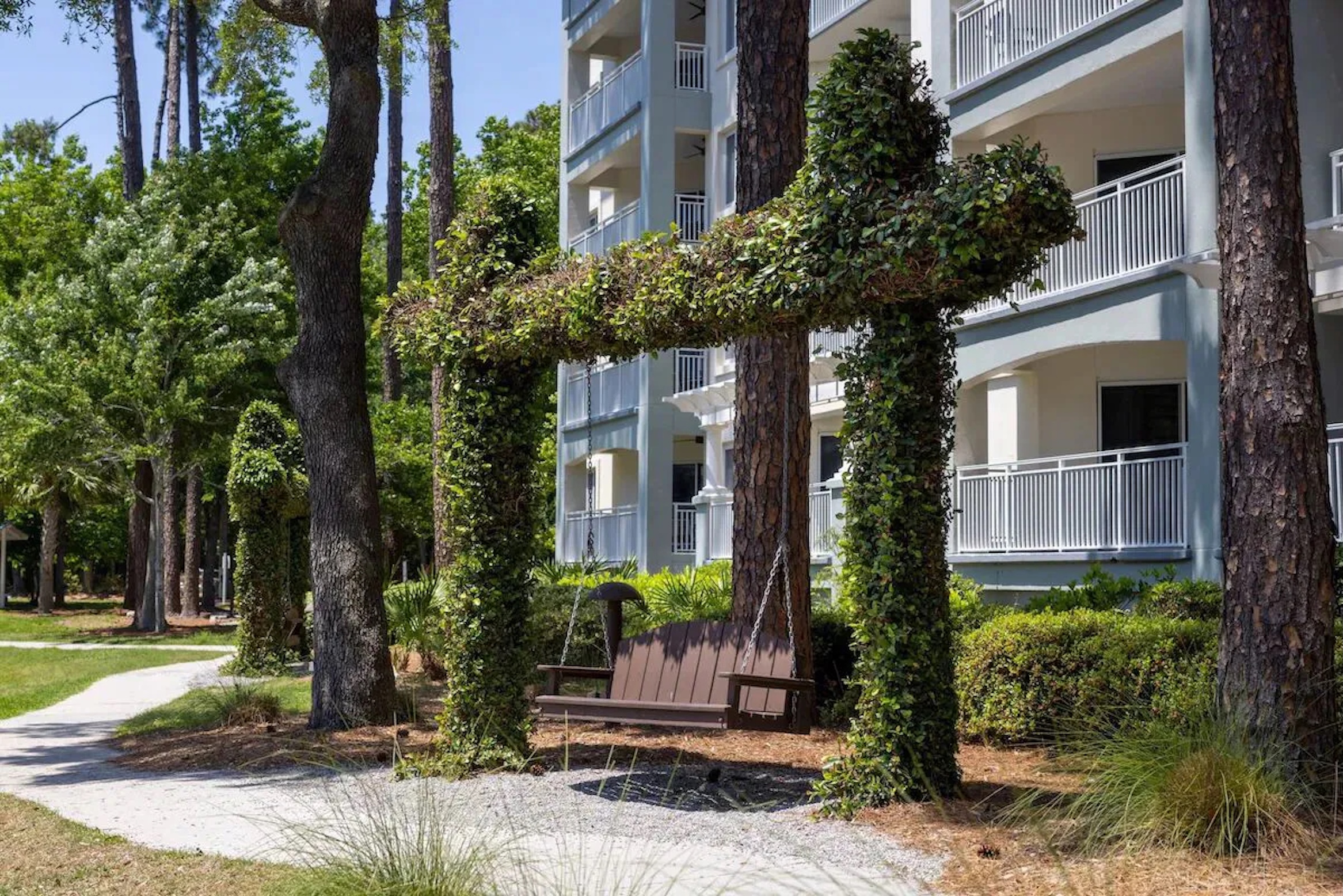 Peaceful garden swing along a shaded path with lush greenery