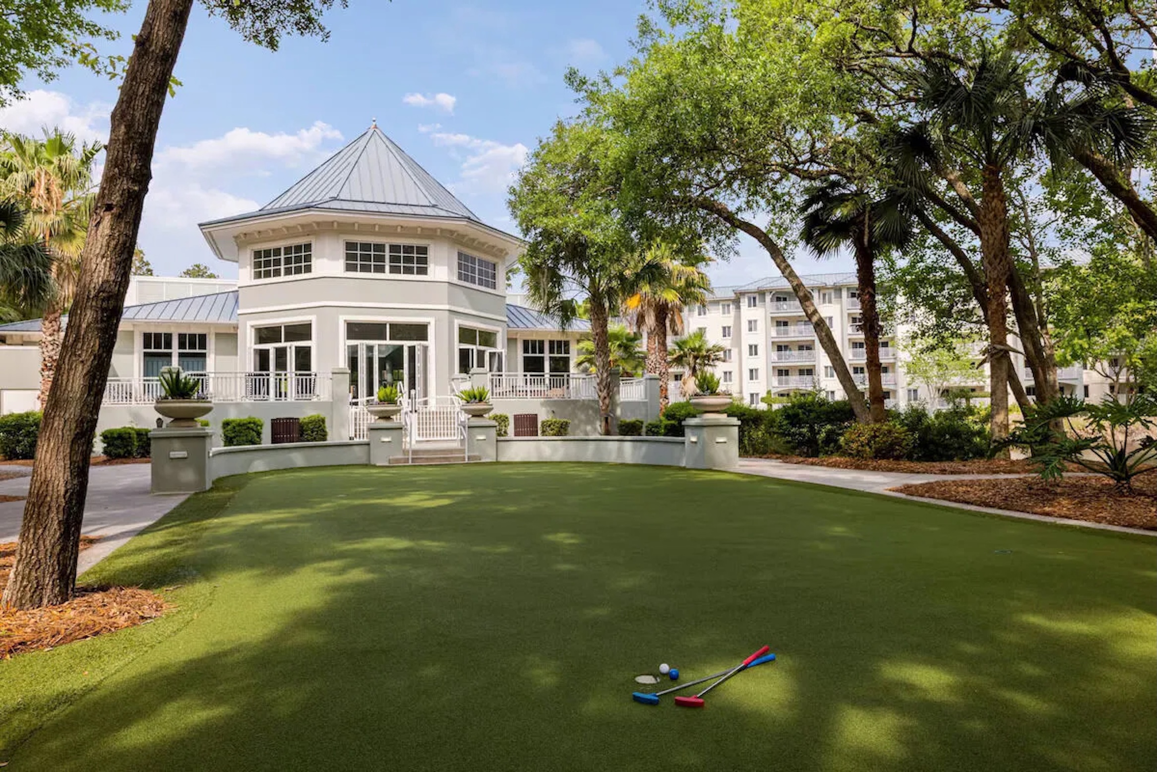 Resort-style putting green and elegant clubhouse framed by lush trees