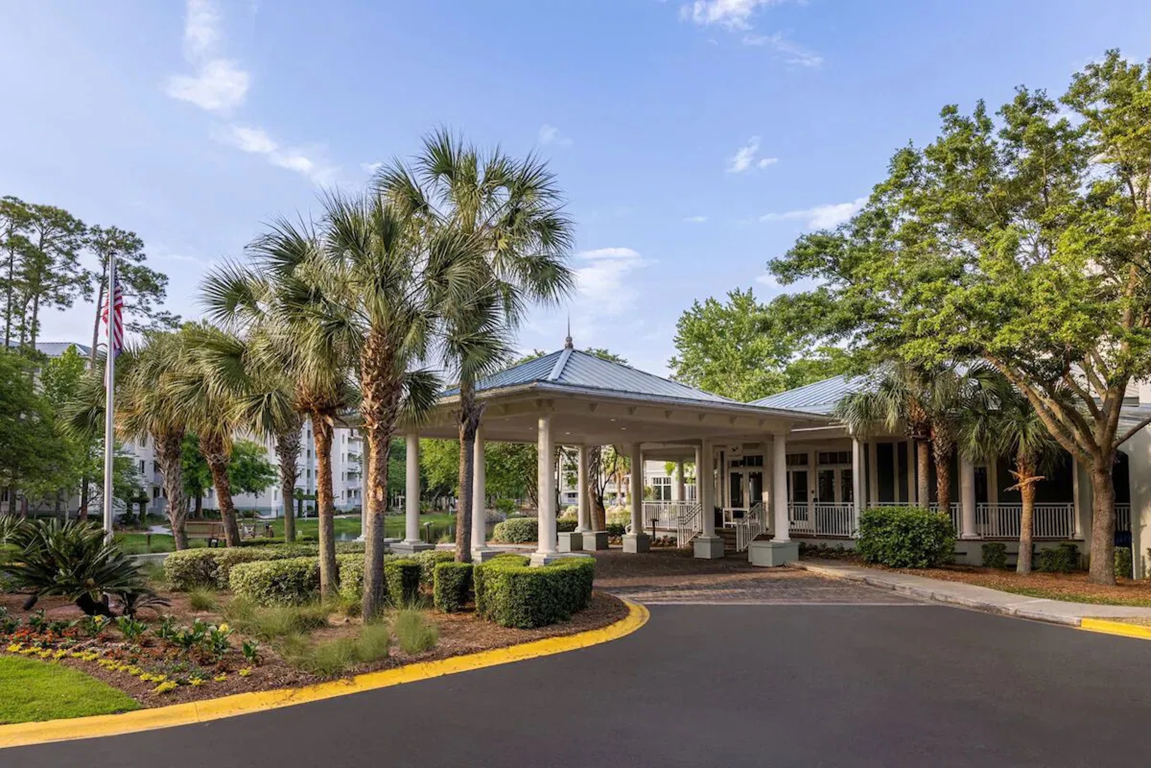 Resort-style entrance with palm-lined drive and welcoming covered portico