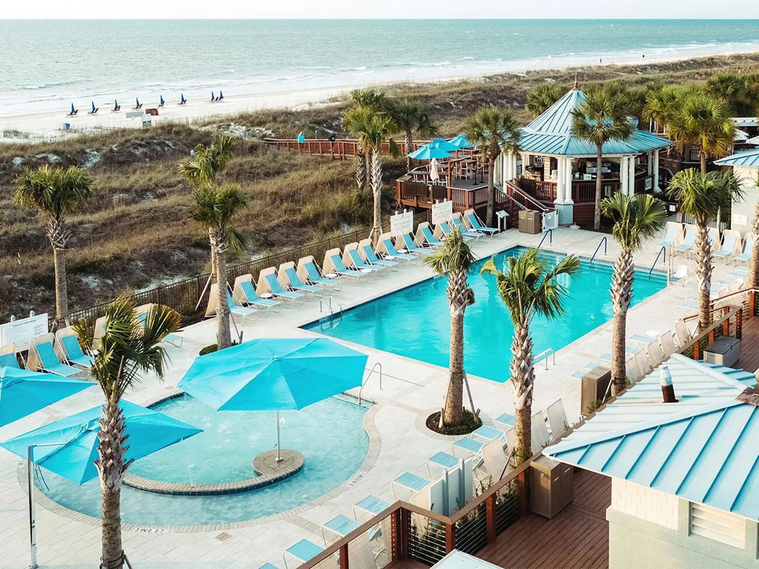 Resort-style beachfront pool deck steps from the sand and sea