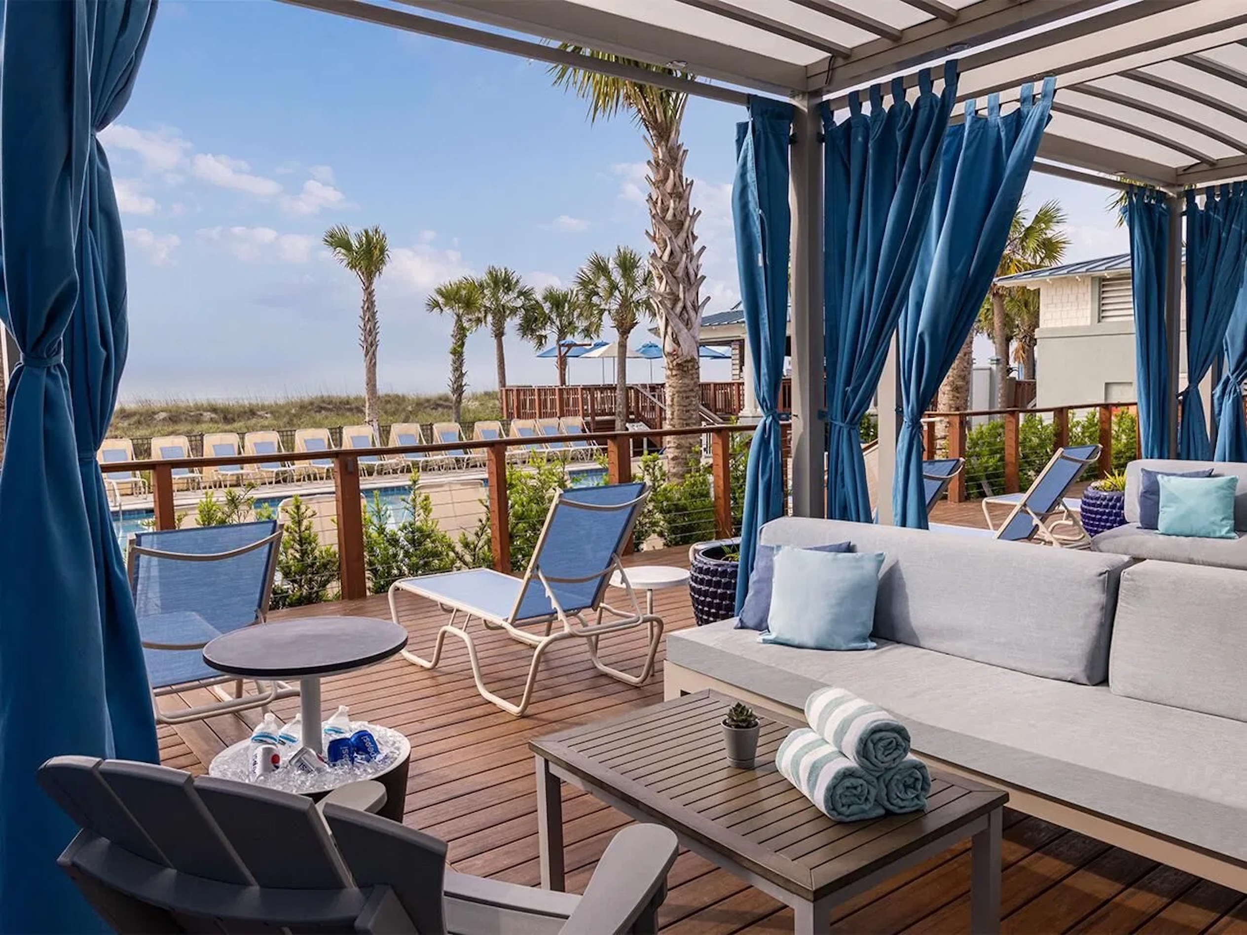 Covered poolside cabana with beach views, palm trees, and resort-style seating