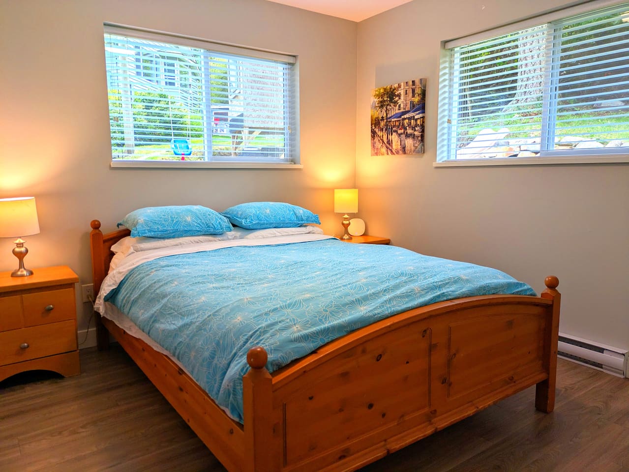 This bedroom has a queen bed that includes two side tables, two lamps, a closet with hangers, and a luggage rack.