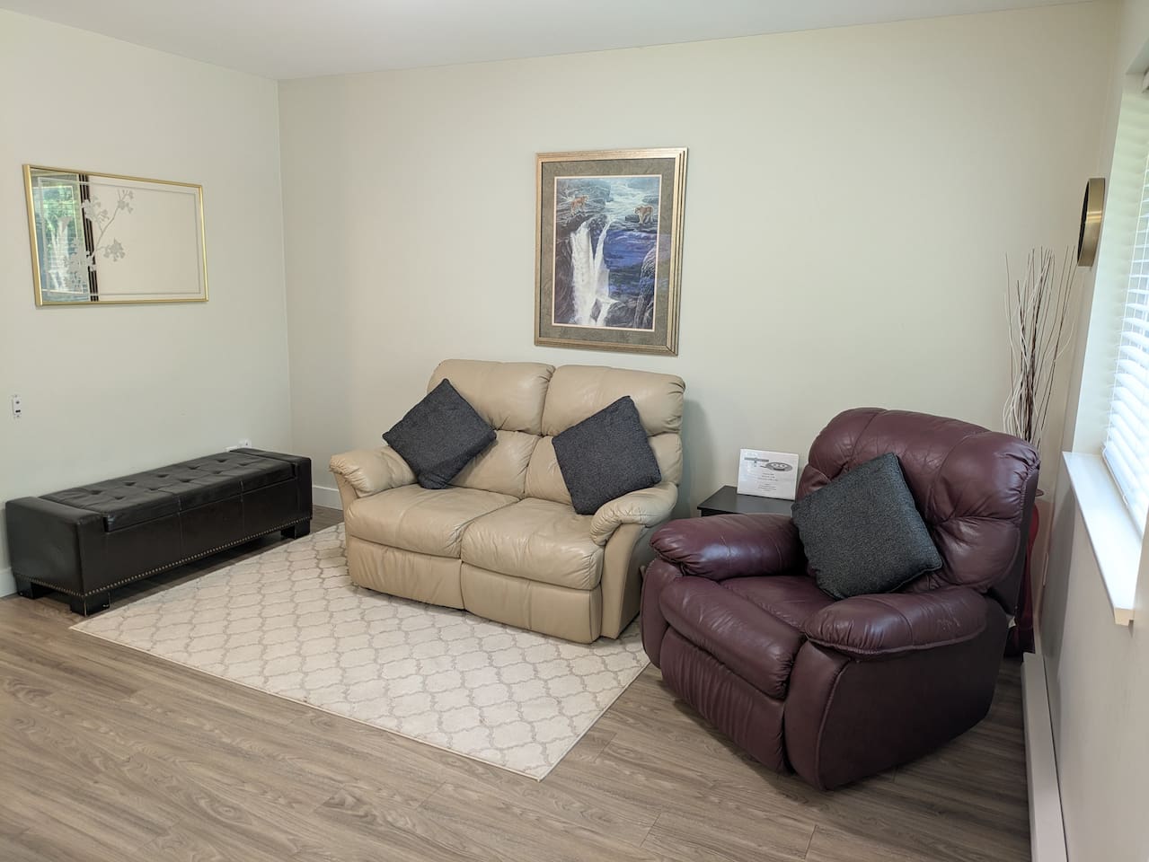 The cozy lounge area includes a reclining loveseat, recliner, and lots of natural light.
