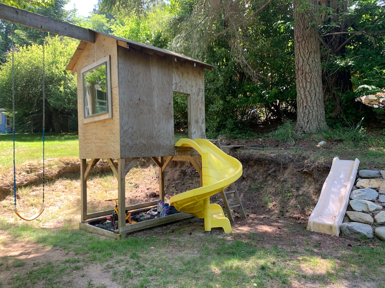 The family-friendly backyard with a playhouse, swings, and a fun spiral slide.