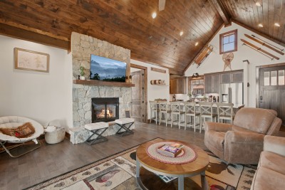 Gather beneath vaulted ceilings in the great room, where a stone fireplace anchors the space and a spacious bar invites easy conversation — the ideal backdrop for game nights, nightcaps, and everyone under one roof.