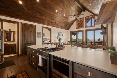 Cook up a feast at the spacious island's gas range while sunlight pours through floor-to-ceiling glass doors, framing endless Blue Ridge peaks — a bright, open heart of the home built for connection.