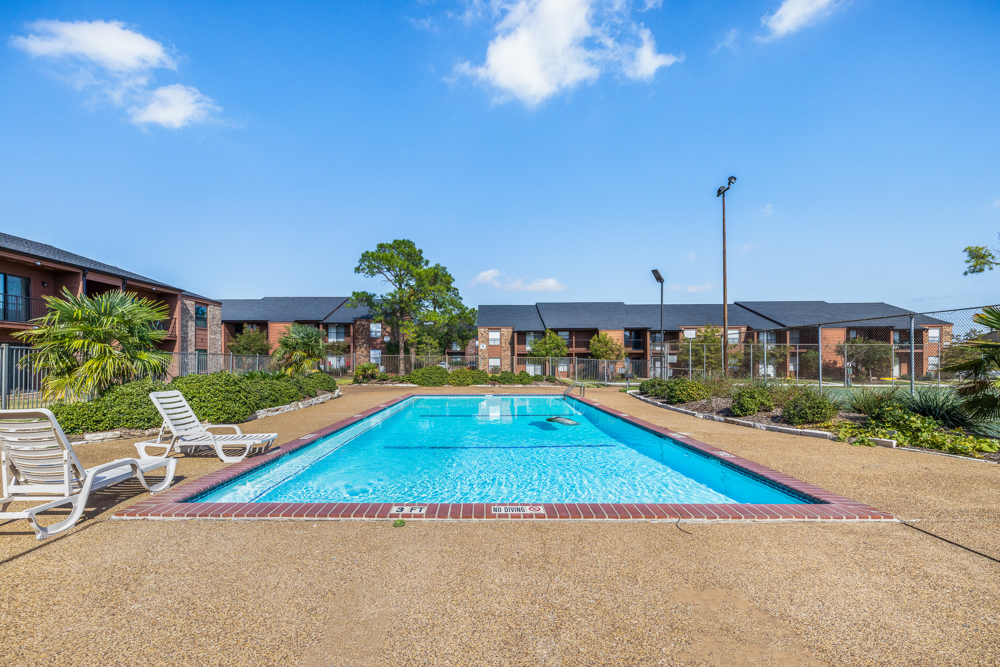 Sunny community pool with lounge chairs and a spacious deck