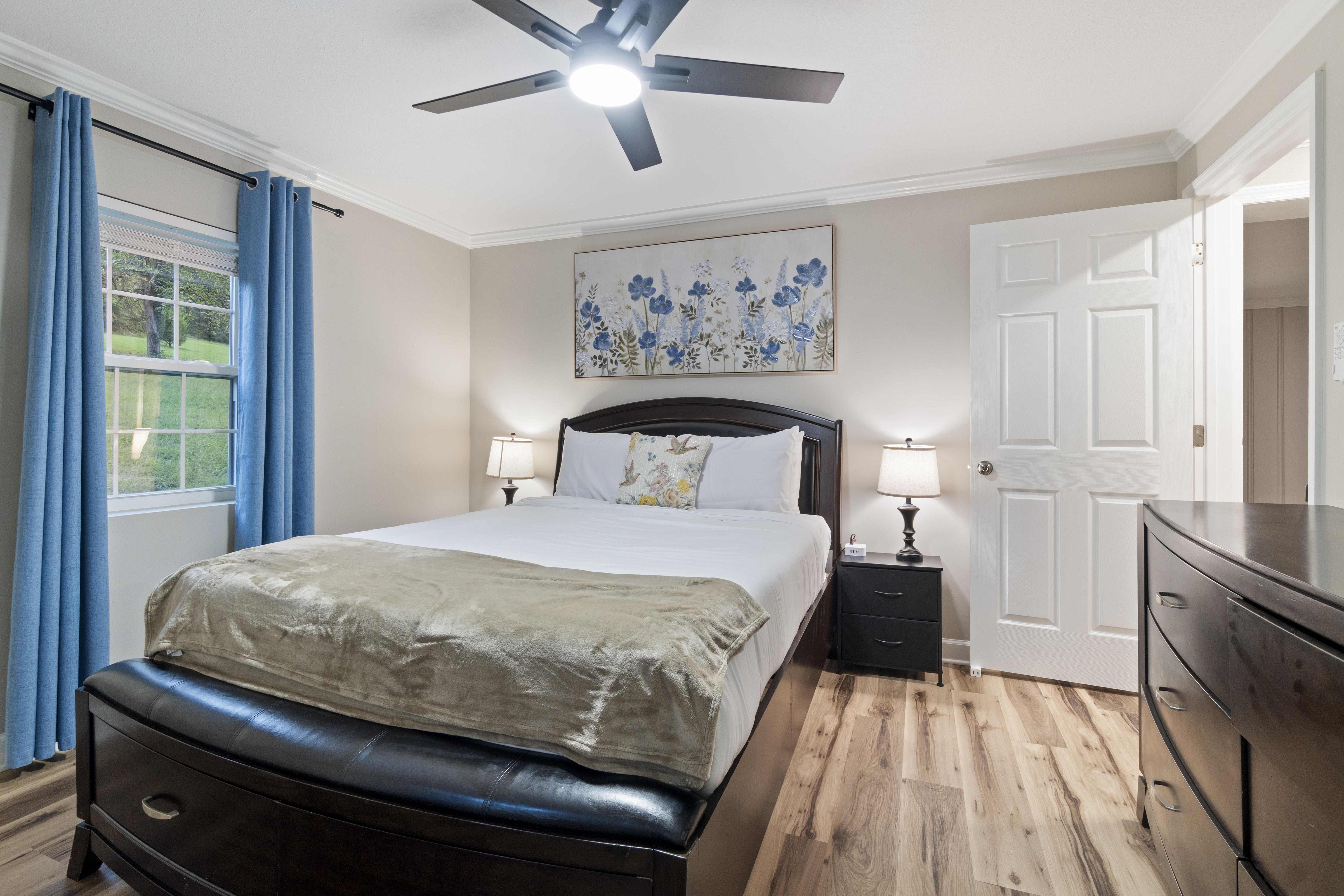 Bright, stylish bedroom with plush bedding, blackout curtains, and ceiling fan