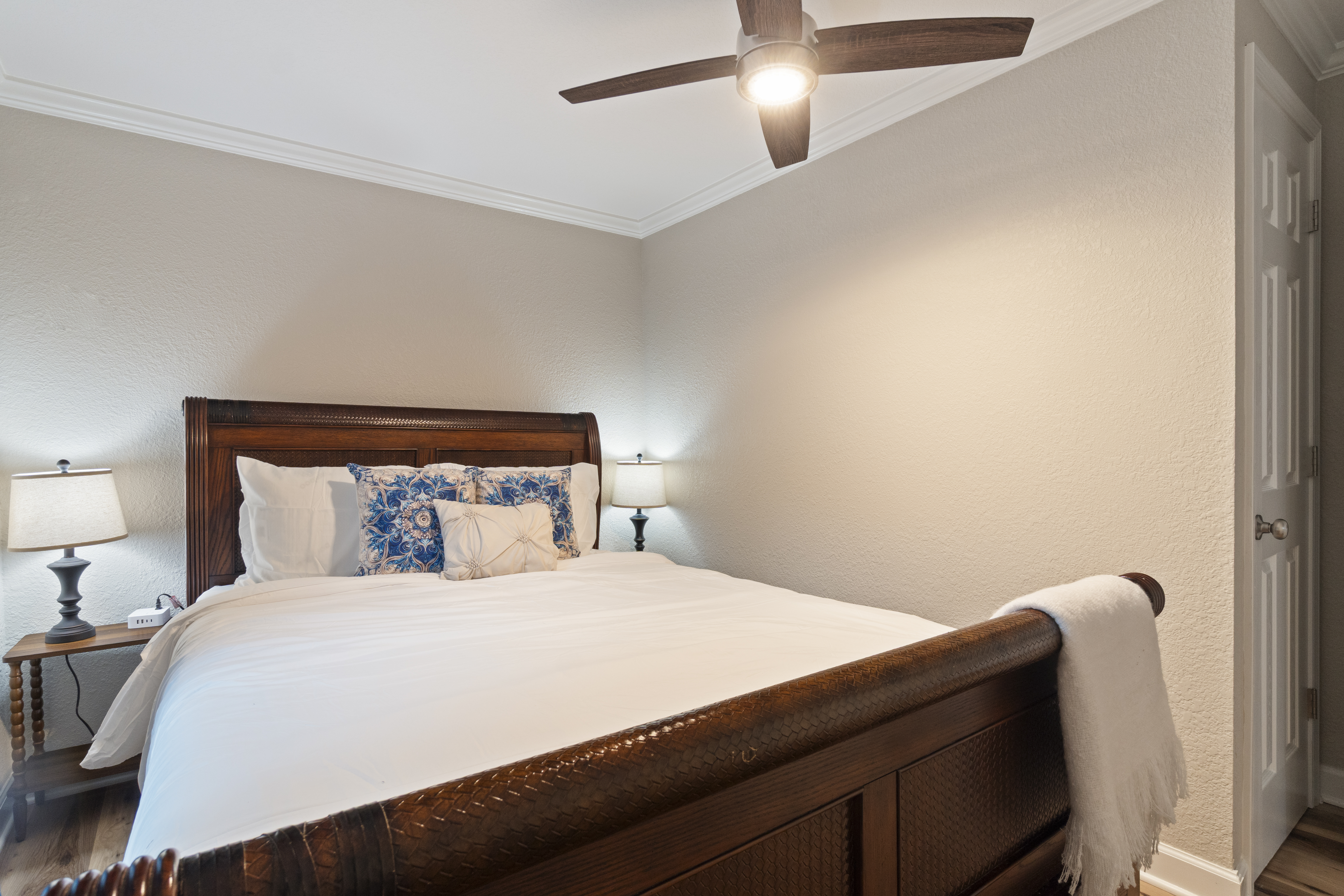 Cozy bedroom with elegant wood bed, soft lighting, and crisp white linens