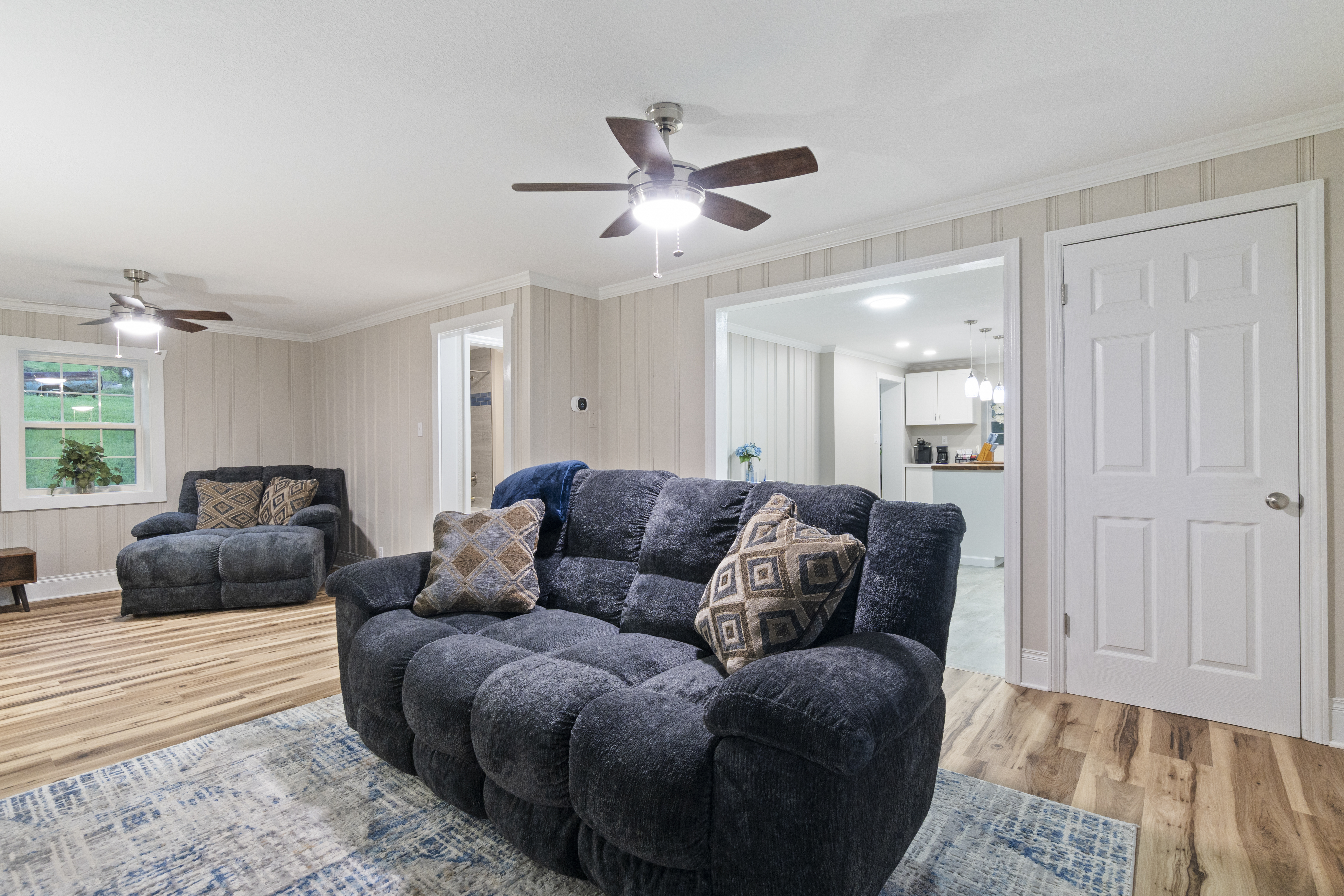 Spacious cozy living room with plush seating and open flow to kitchen