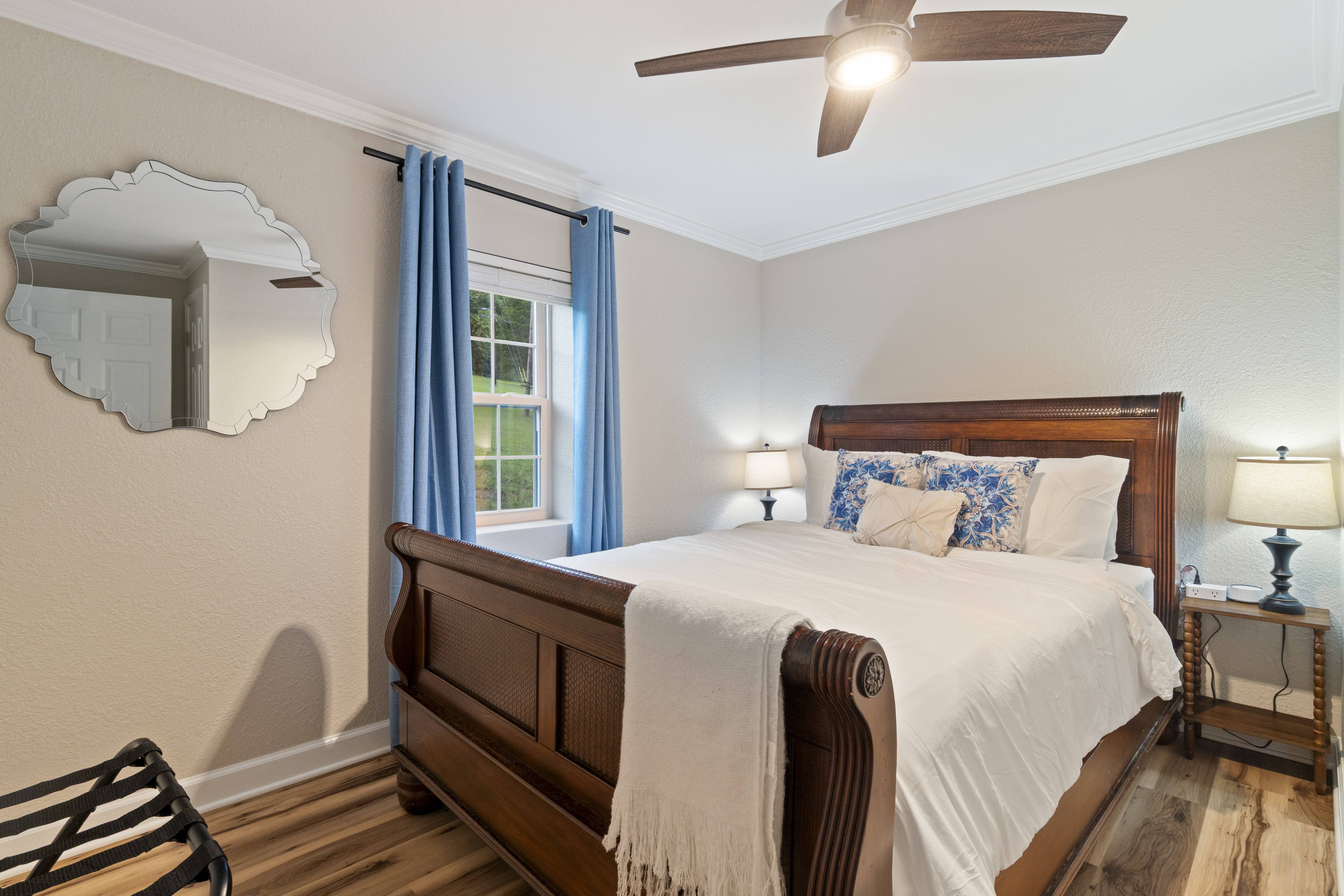 Cozy queen bedroom with elegant wood bed, blue accents, and ceiling fan