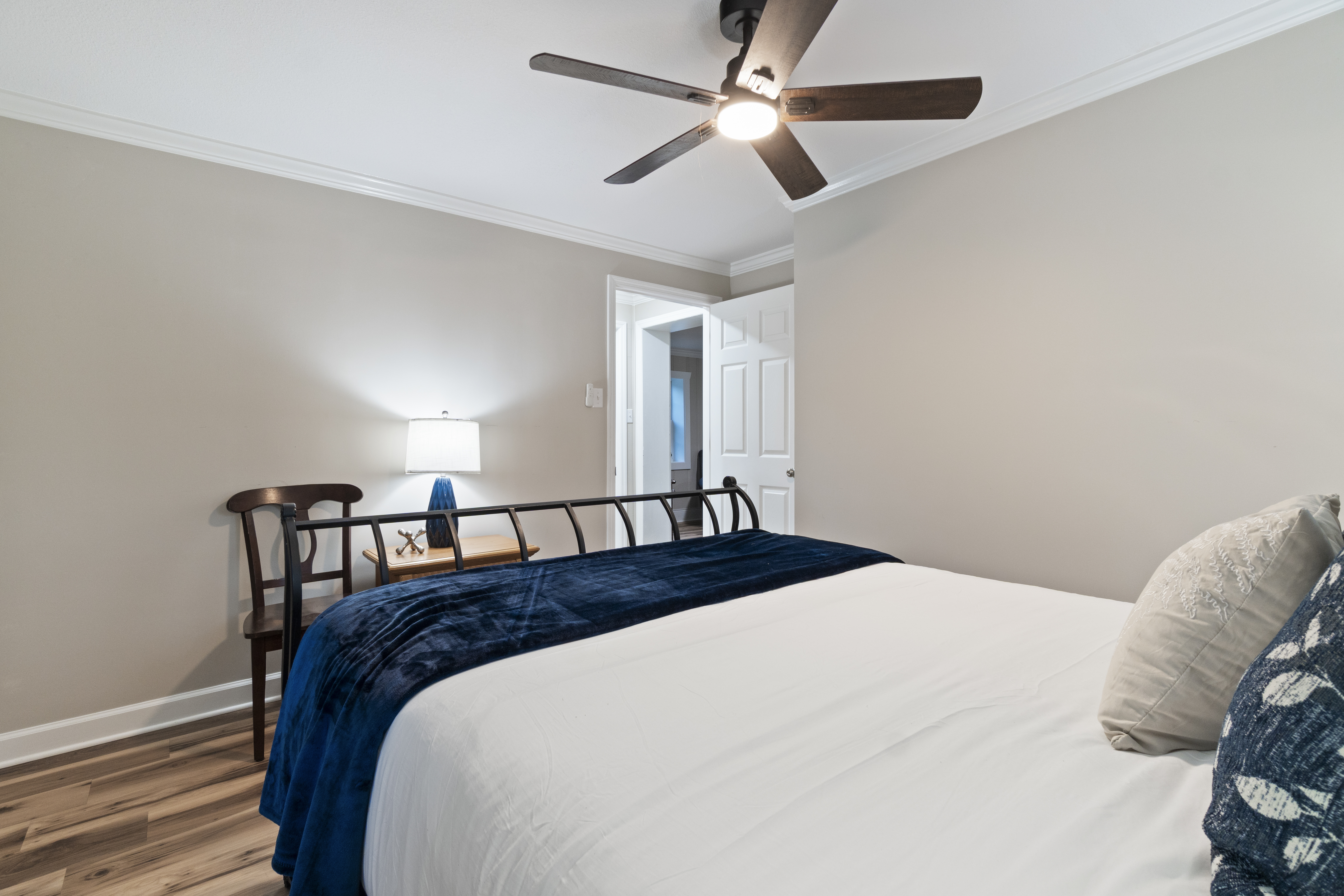 Cozy modern bedroom with crisp linens, ceiling fan, and stylish navy accents