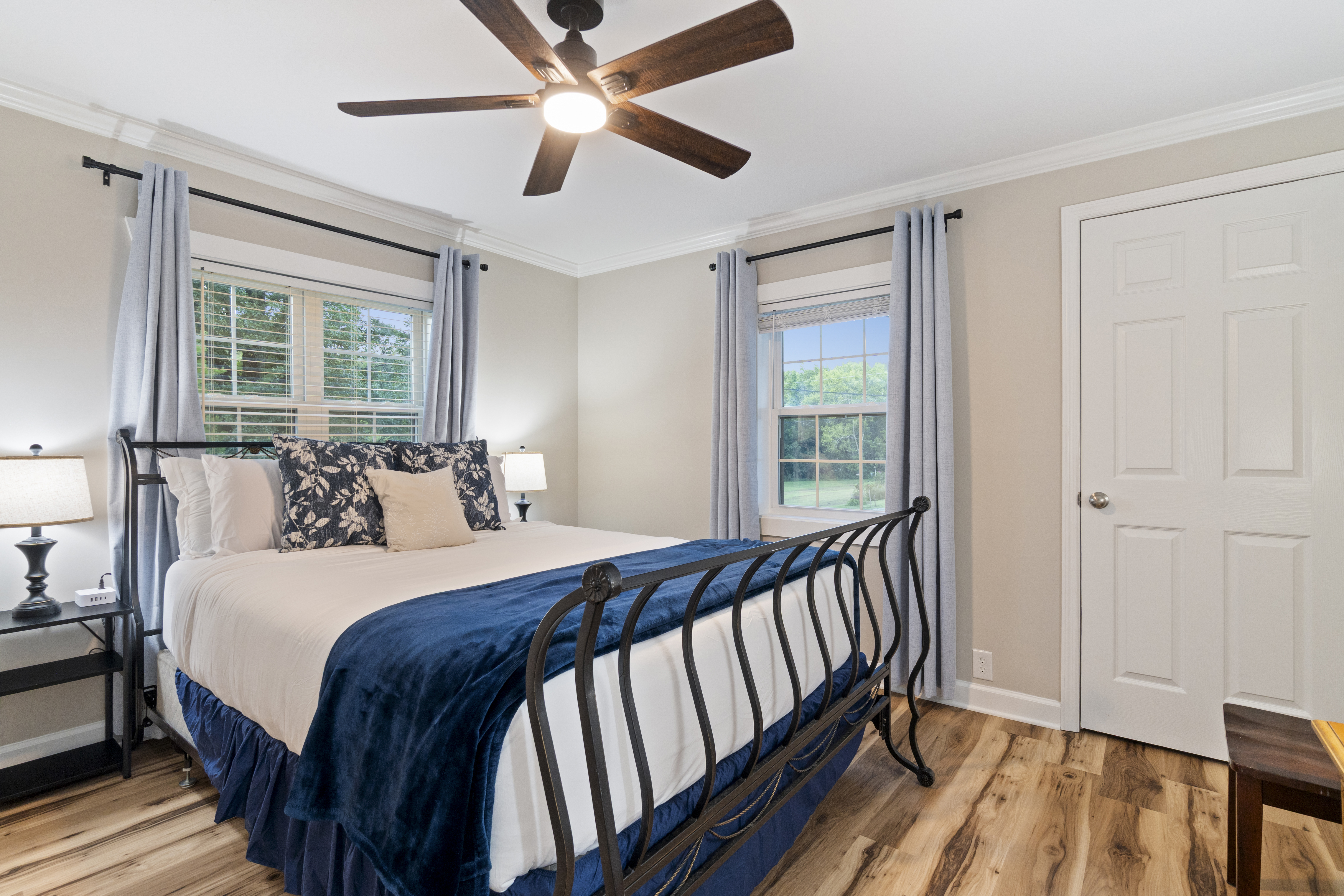 Bright, cozy bedroom with king bed, natural light, and stylish navy accents