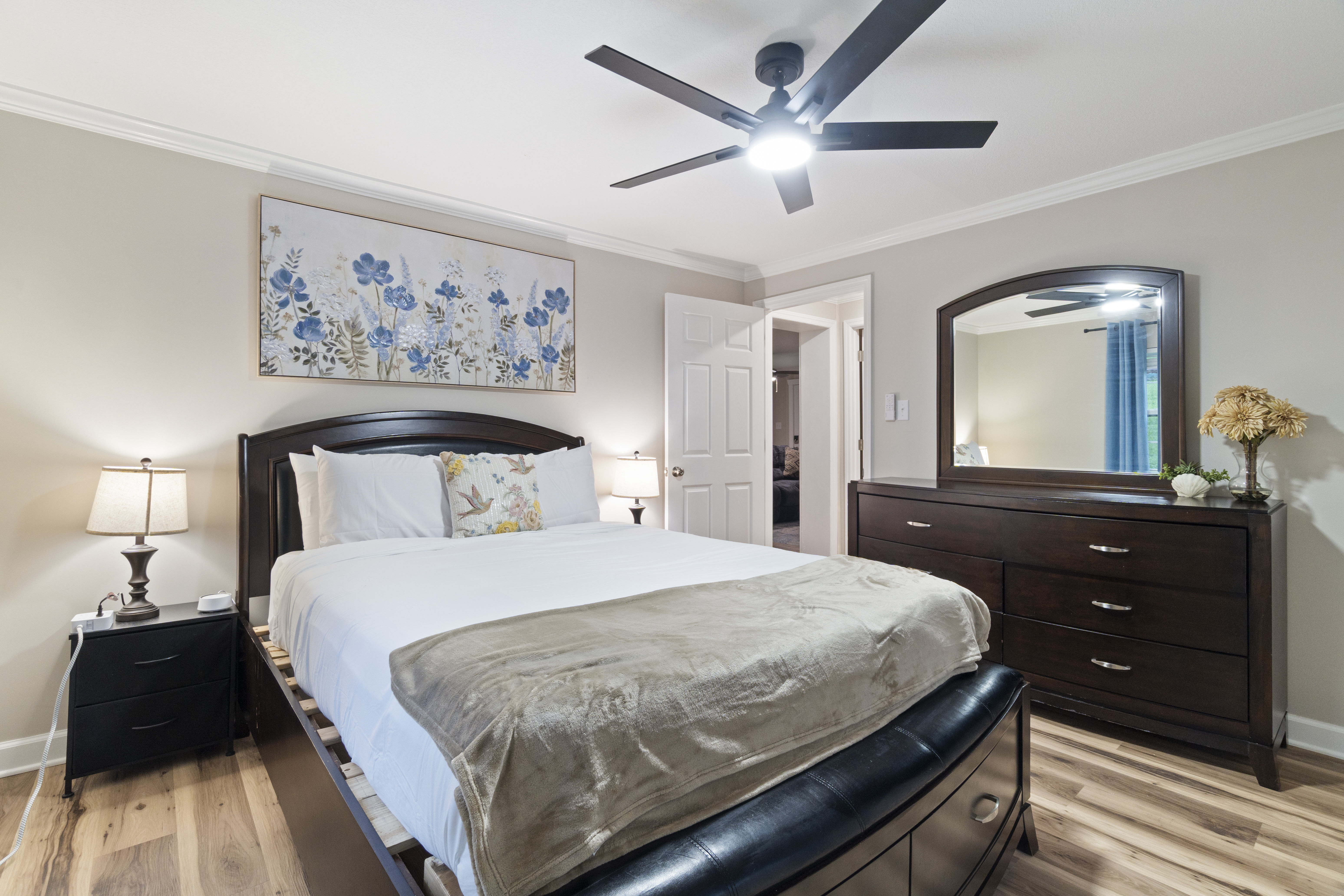 Cozy, stylish bedroom with dark wood furnishings and ceiling fan