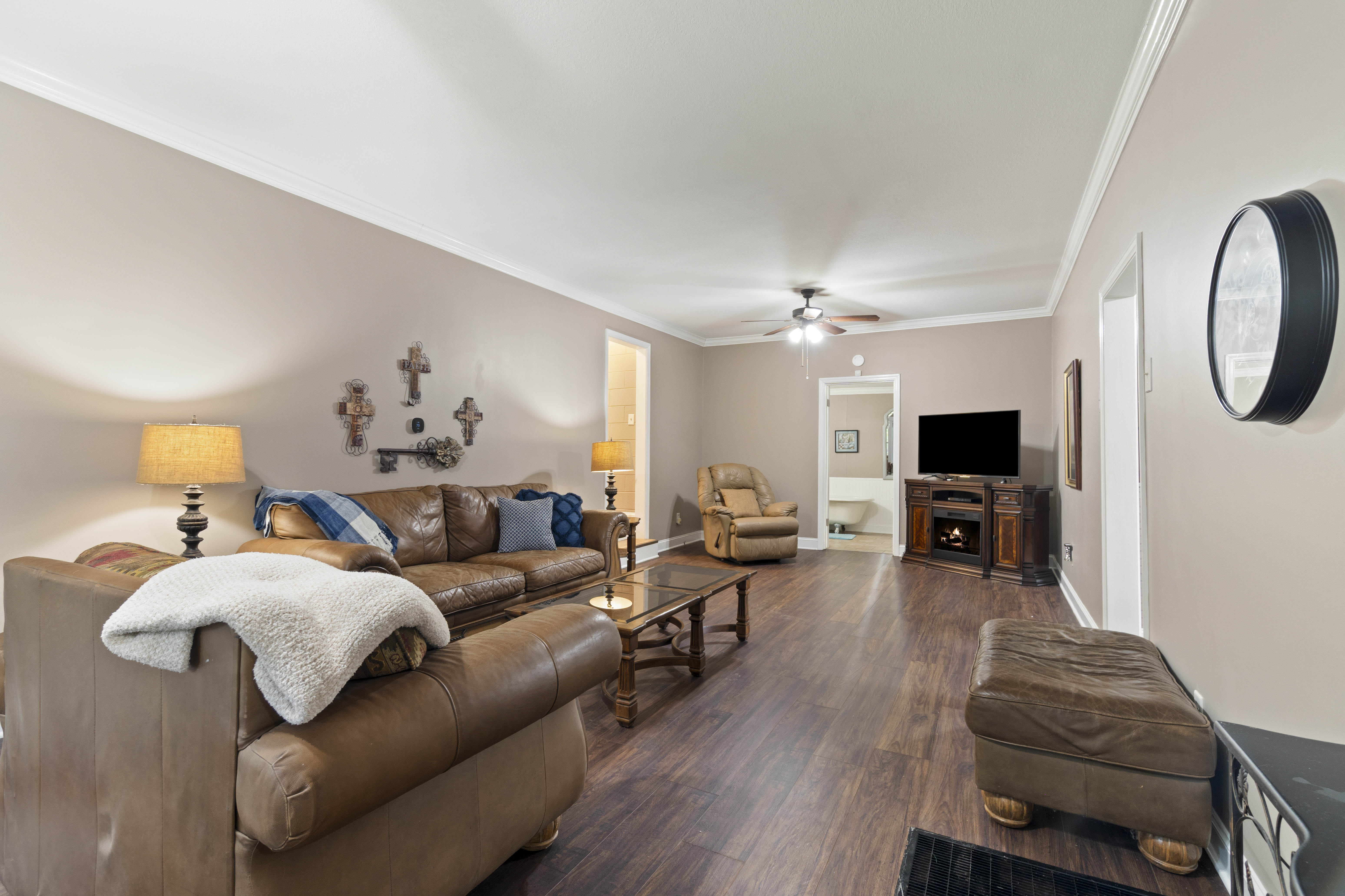 Spacious cozy living room with leather seating, TV, and fireplace