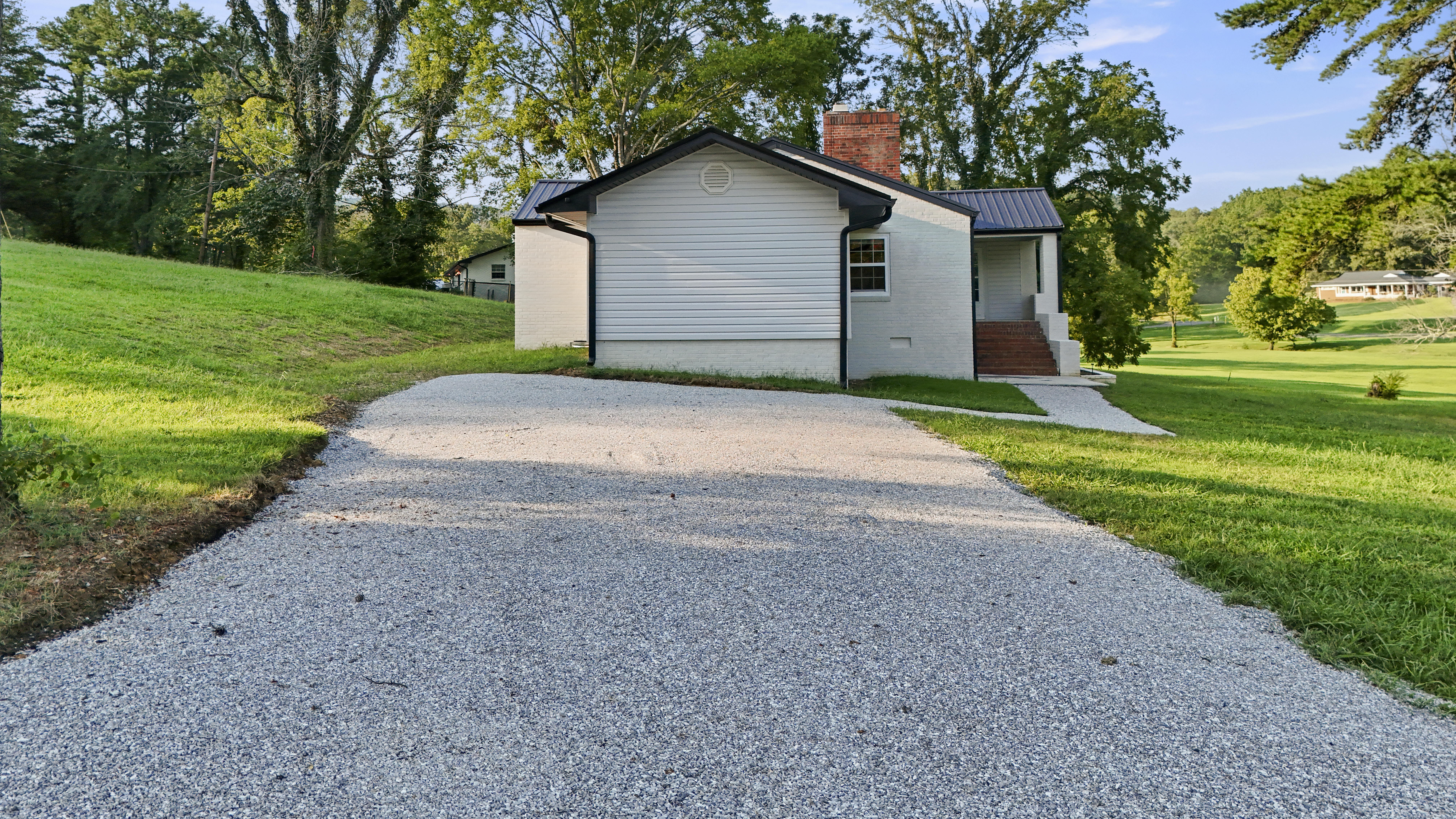 Fresh gravel drive and peaceful tree-lined setting with spacious green lawn