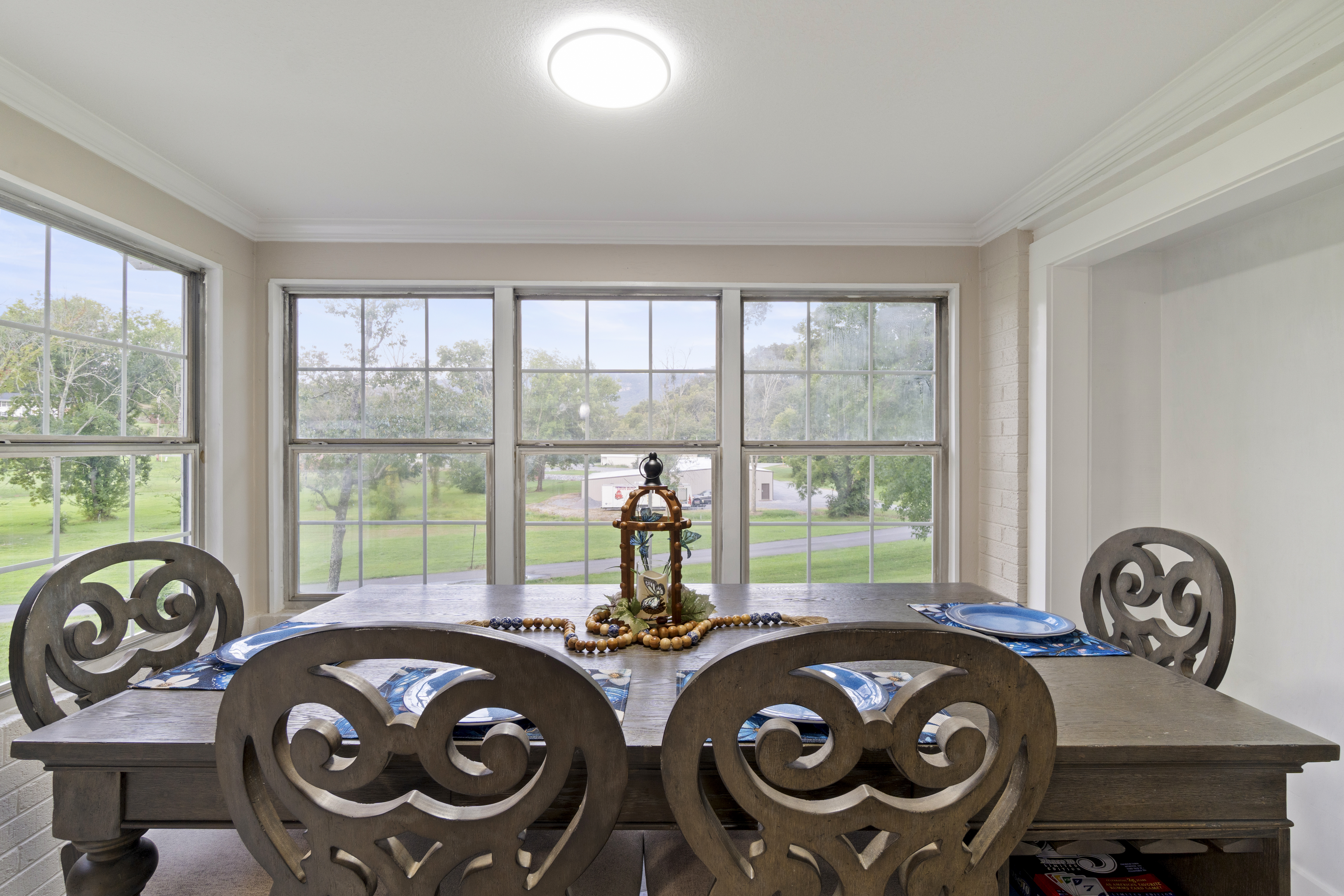 Sunny dining room with large windows and peaceful green views