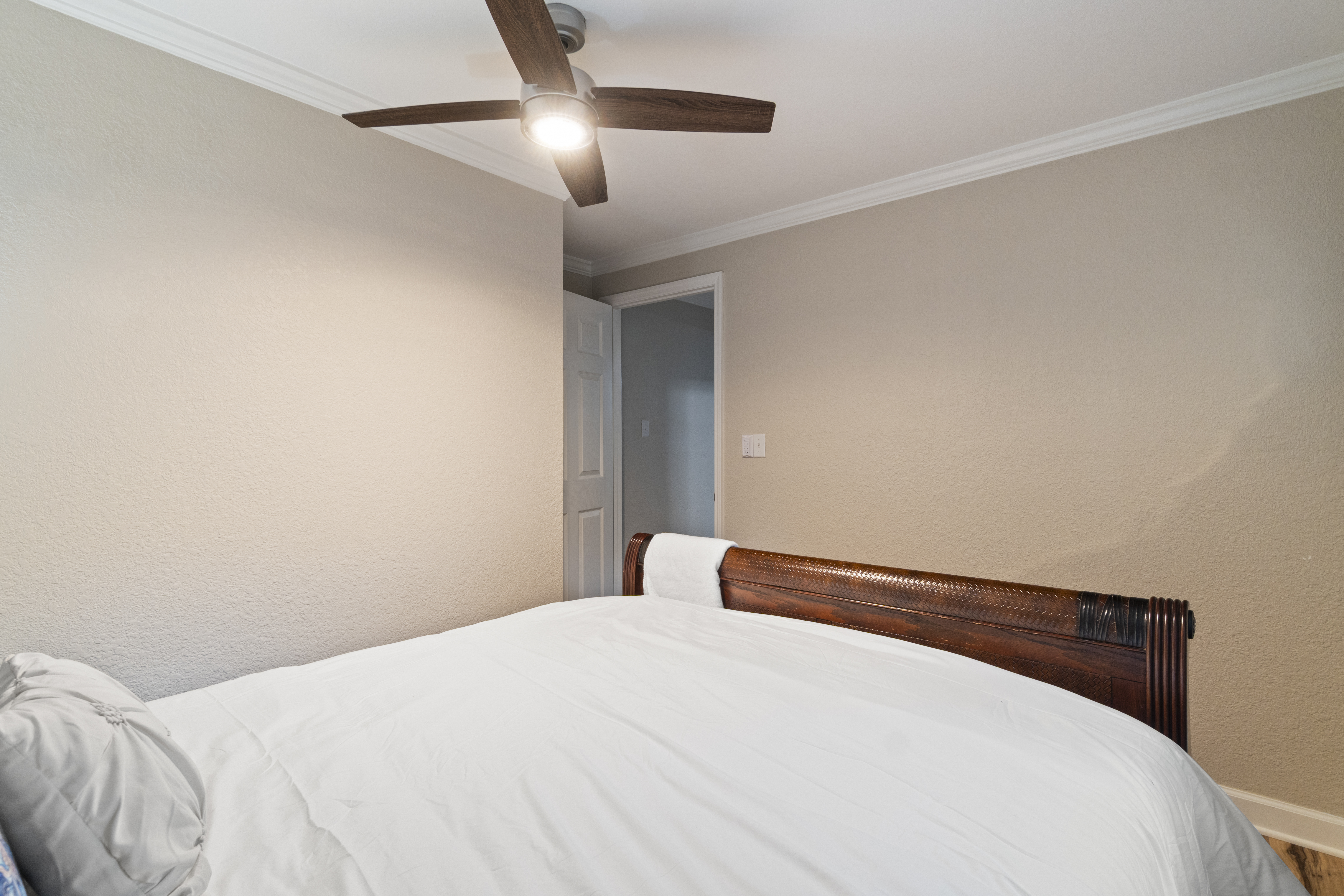 Cozy bedroom with classic wood bed, soft lighting, and clean neutral style