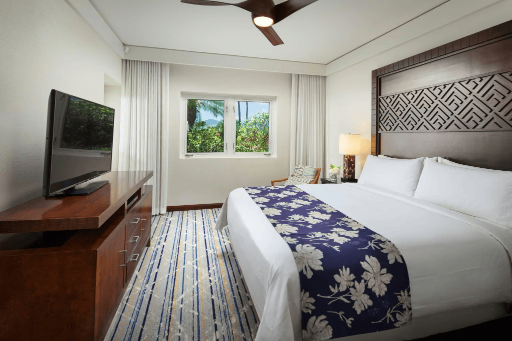 Bright tropical king bedroom with garden views, TV, and elegant island-inspired decor