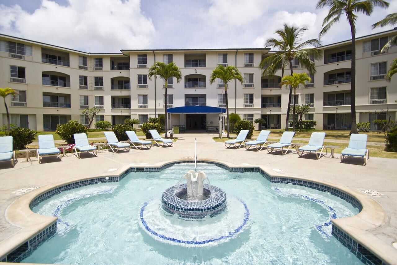 Resort-style pool courtyard with fountain, loungers, and tropical palms