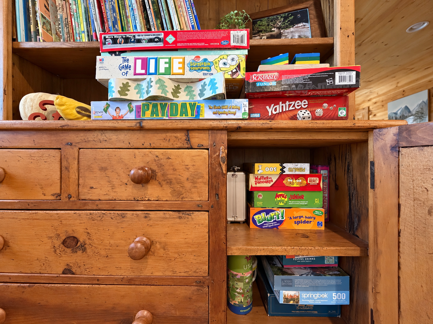 Game cabinet stocked with books, puzzles, and games for all ages