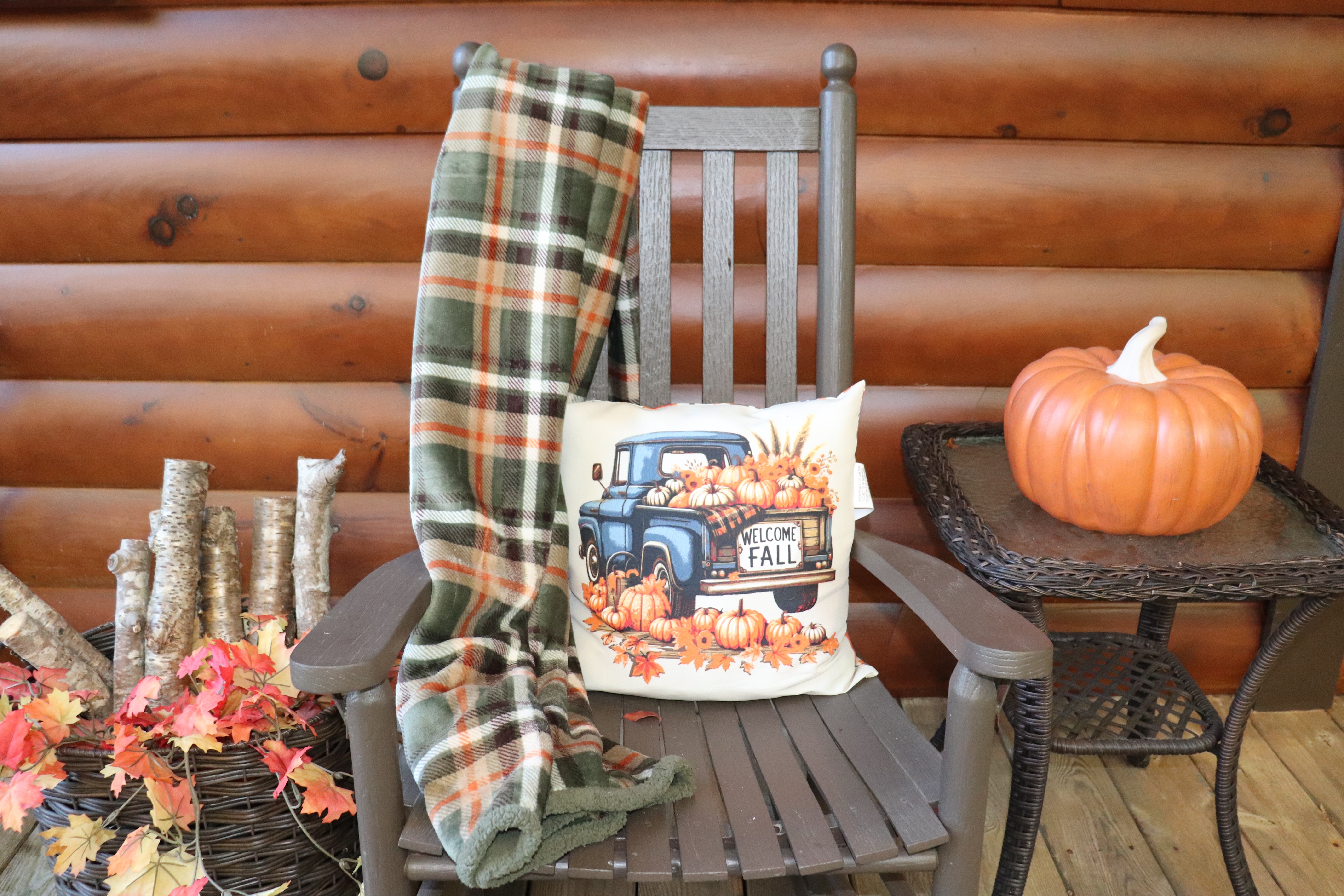 Cozy cabin porch with fall décor, plaid throw, and rustic autumn charm