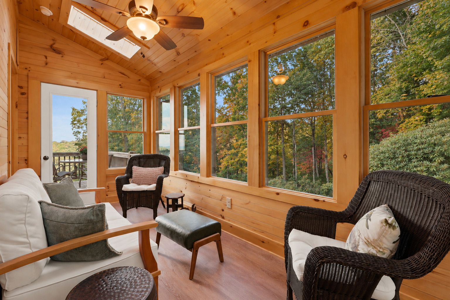 Sun-filled wood-paneled sunroom with cozy seating and serene forest views