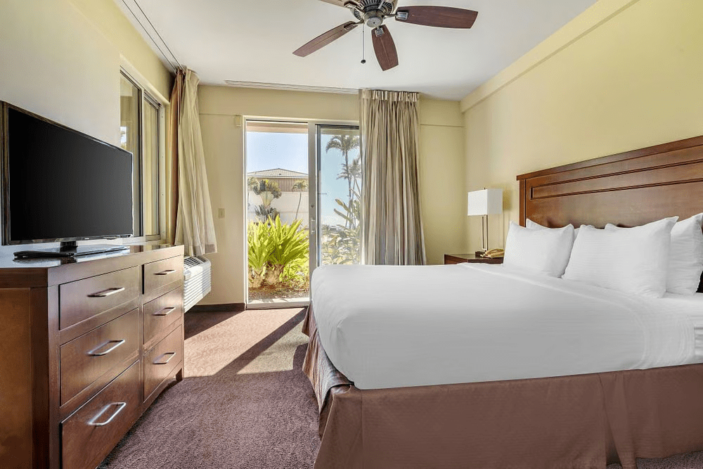 Bright king bedroom with patio access and tropical garden views