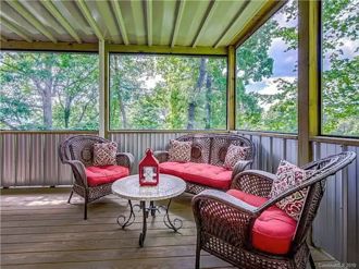Screened-in porch with cozy seating and peaceful wooded views
