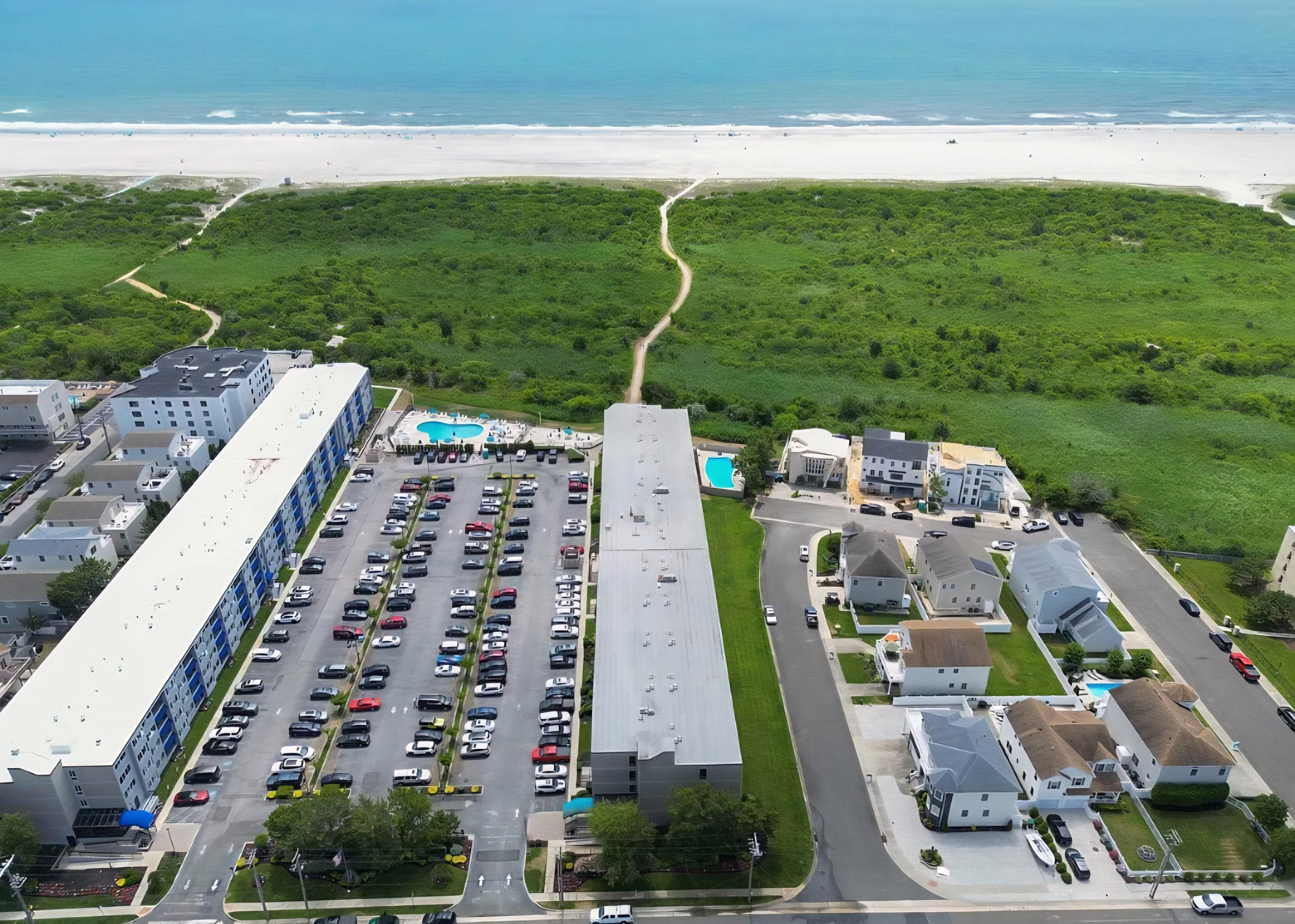 Aerial beachside stay with pool, parking, and direct beach access