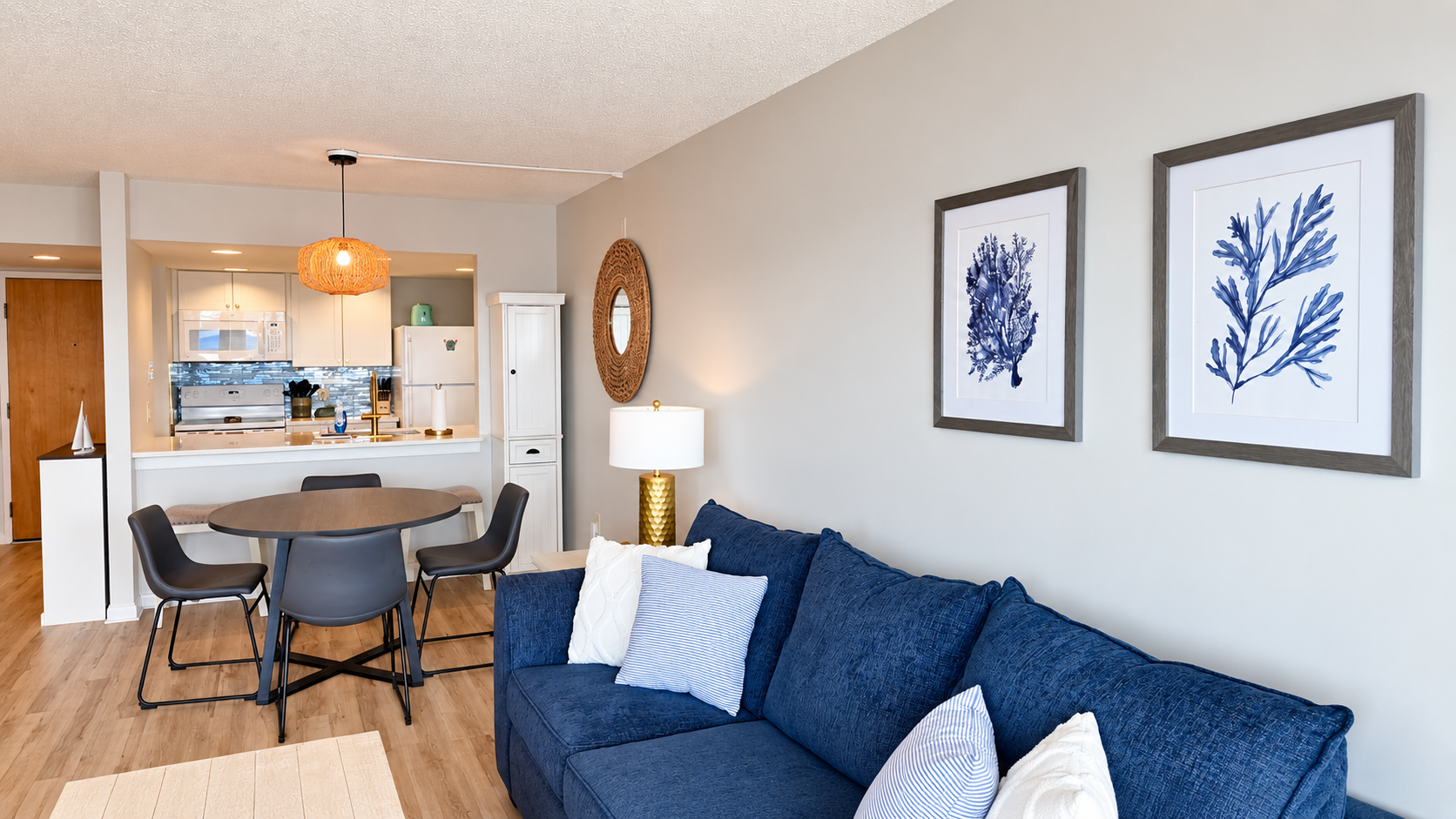 Bright coastal living space with comfy sofa, dining area, and open kitchen