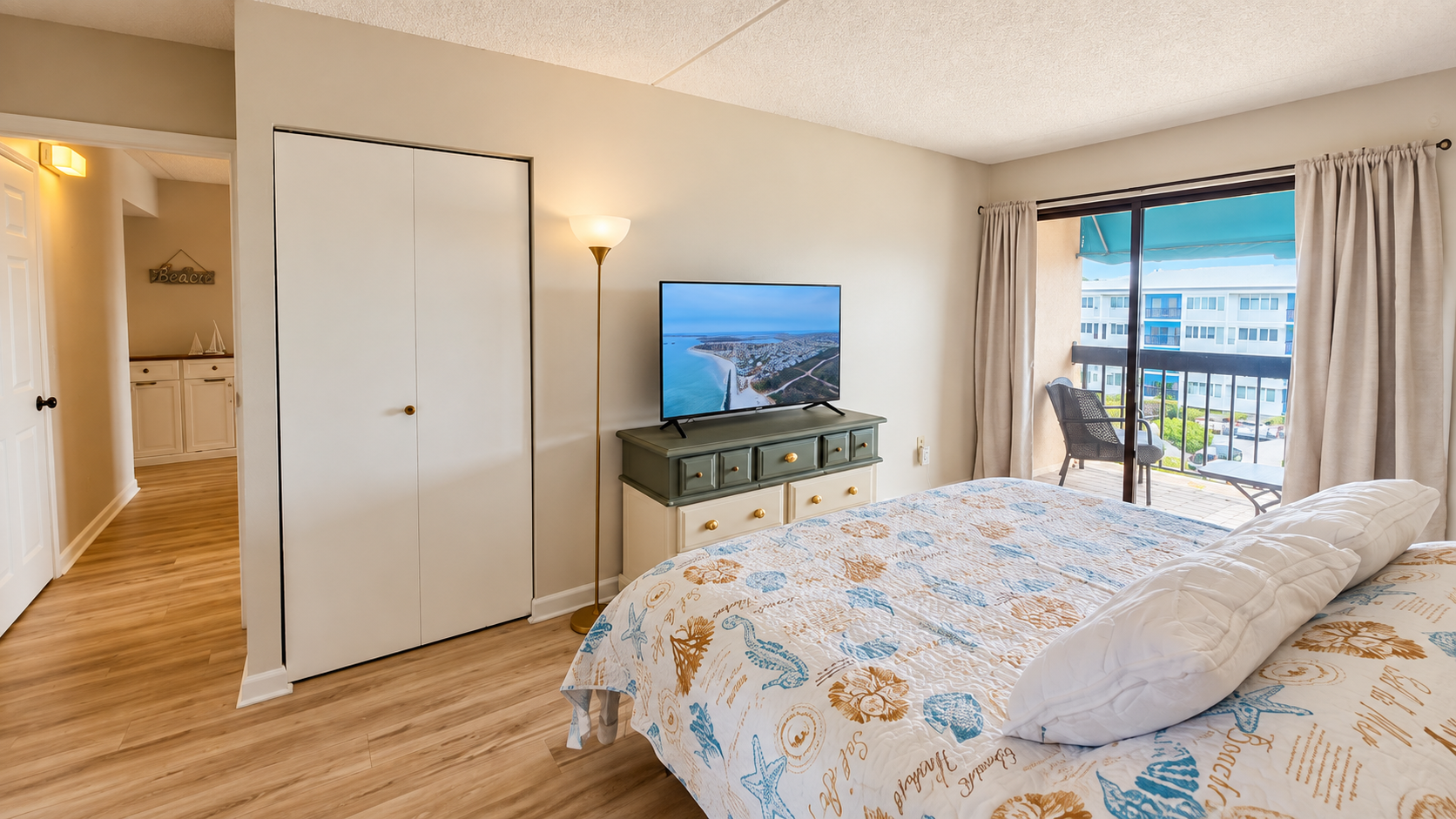 Coastal-style bedroom with TV, private balcony, and water-view seating
