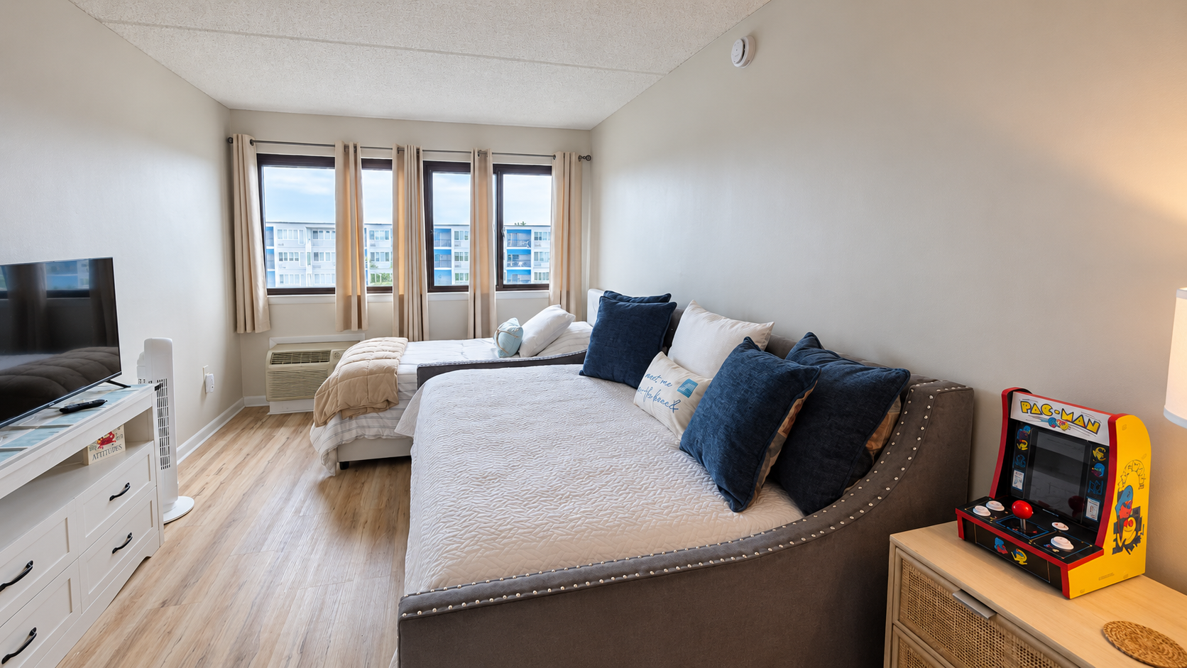 Bright double-bedroom with TV, natural light, and a fun arcade game