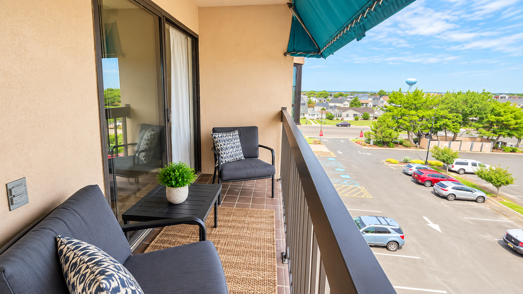 Private furnished balcony with shaded seating and open neighborhood views