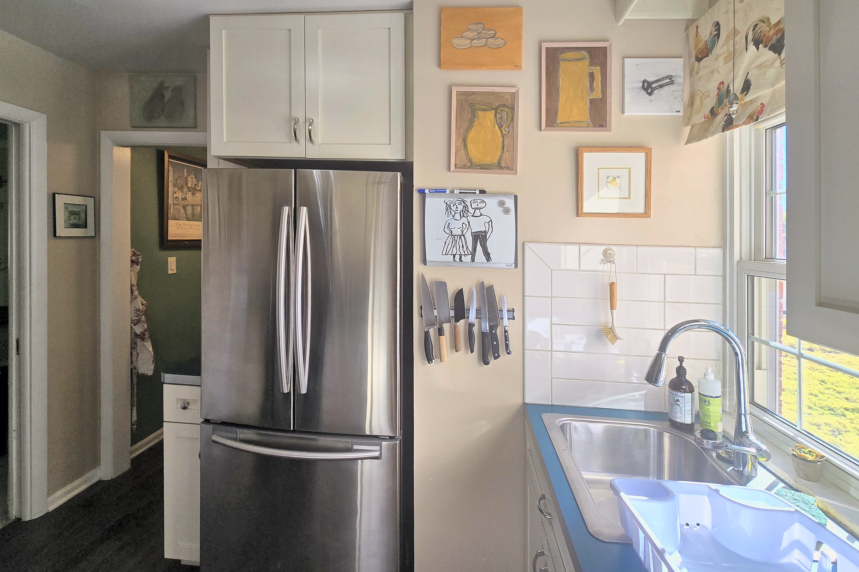 Bright, art-filled kitchen with sunny window and stainless appliances