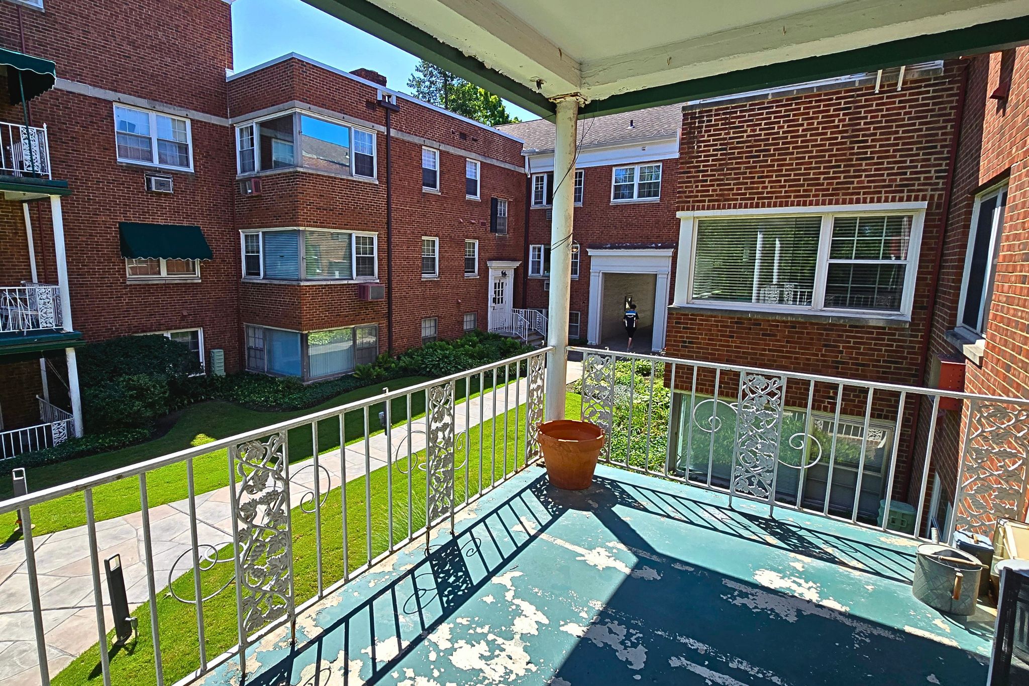Covered private balcony overlooking a sunny, landscaped courtyard