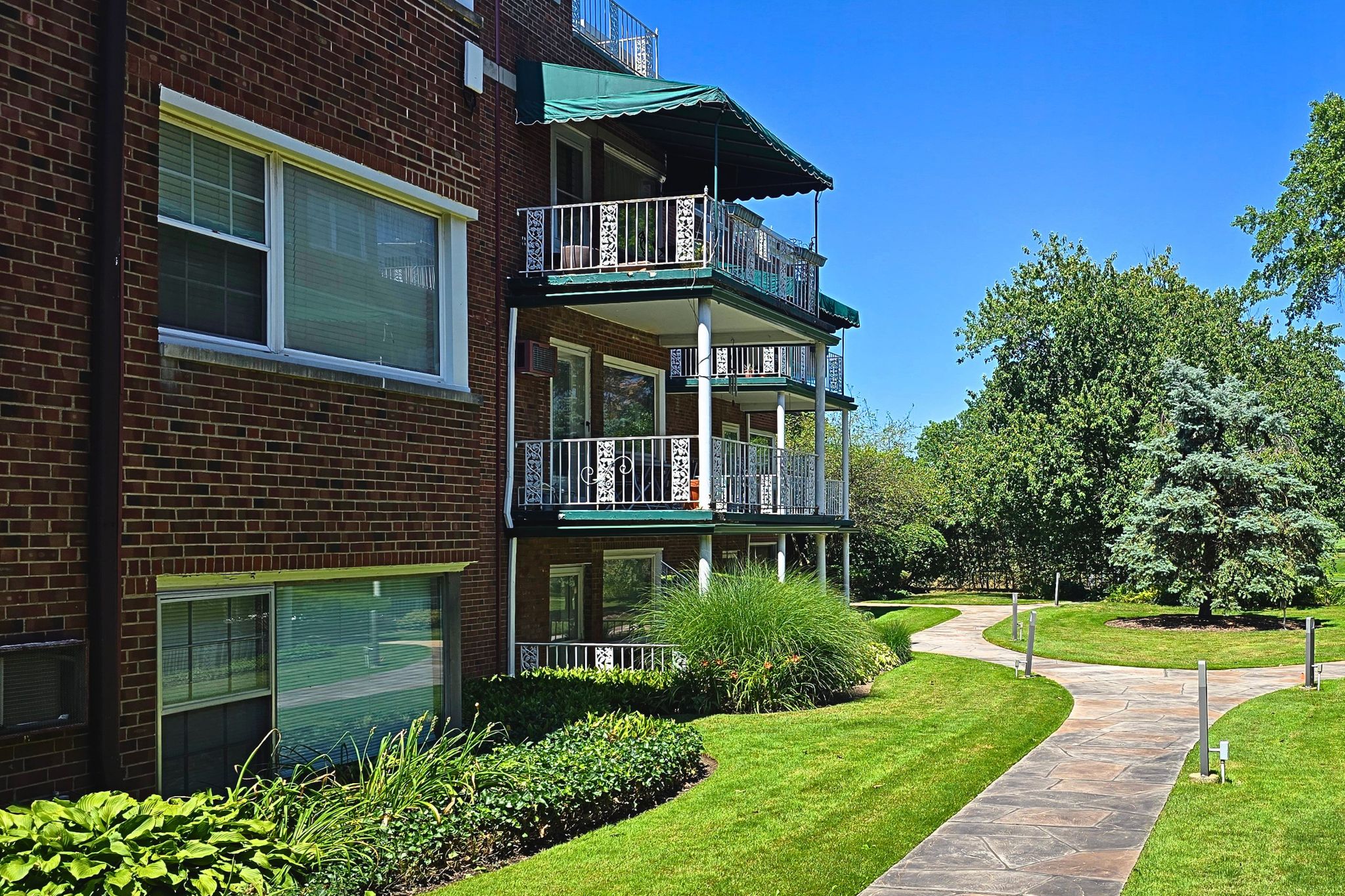 Charming brick building with private balconies and serene landscaped grounds
