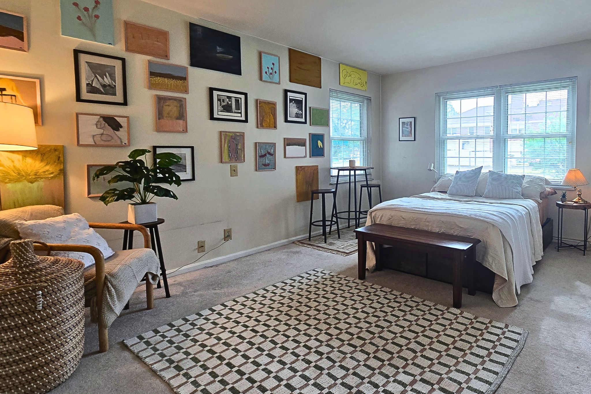 Bright, art-filled bedroom with cozy seating and abundant natural light
