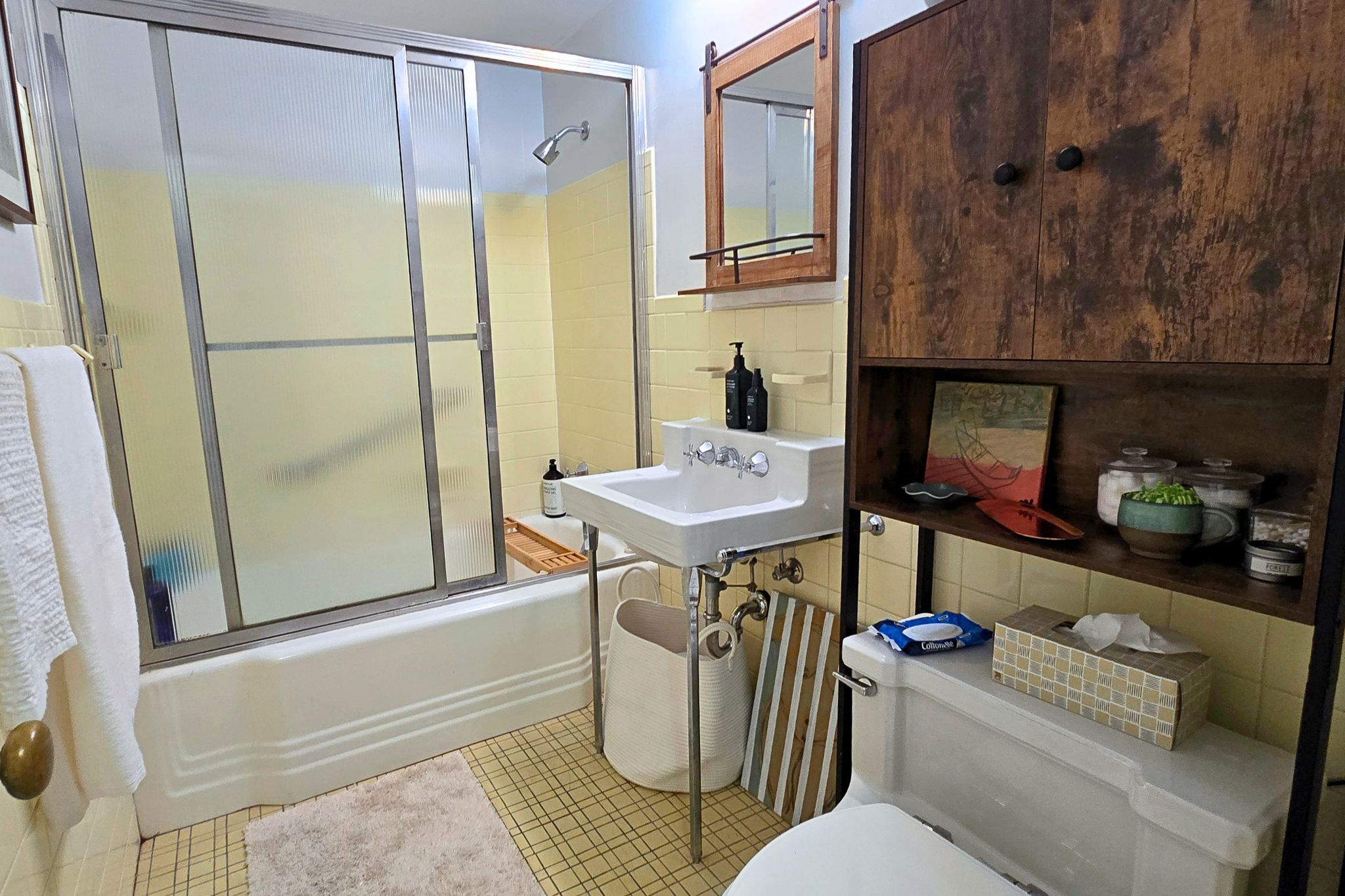 Cozy full bath with tub/shower combo and warm rustic storage accents