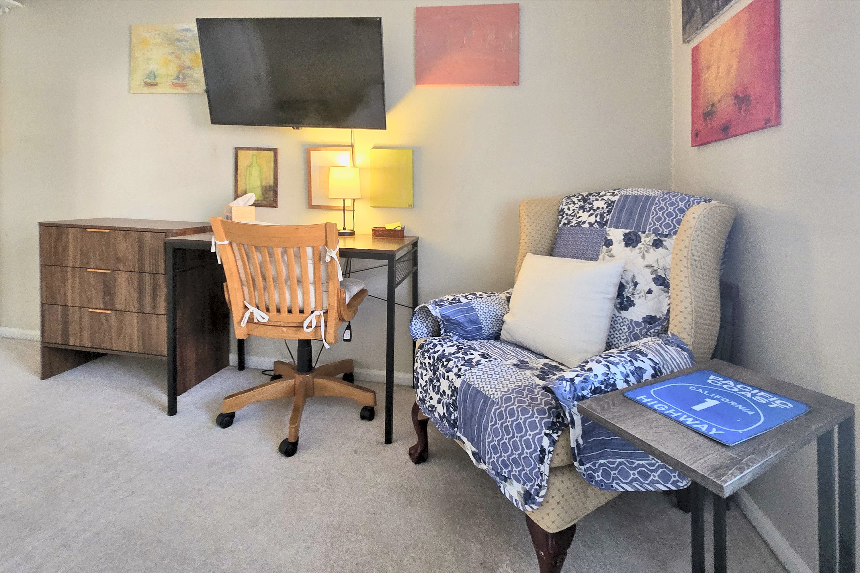 Second bedroom corner with a desk, wall-mounted TV and armchair