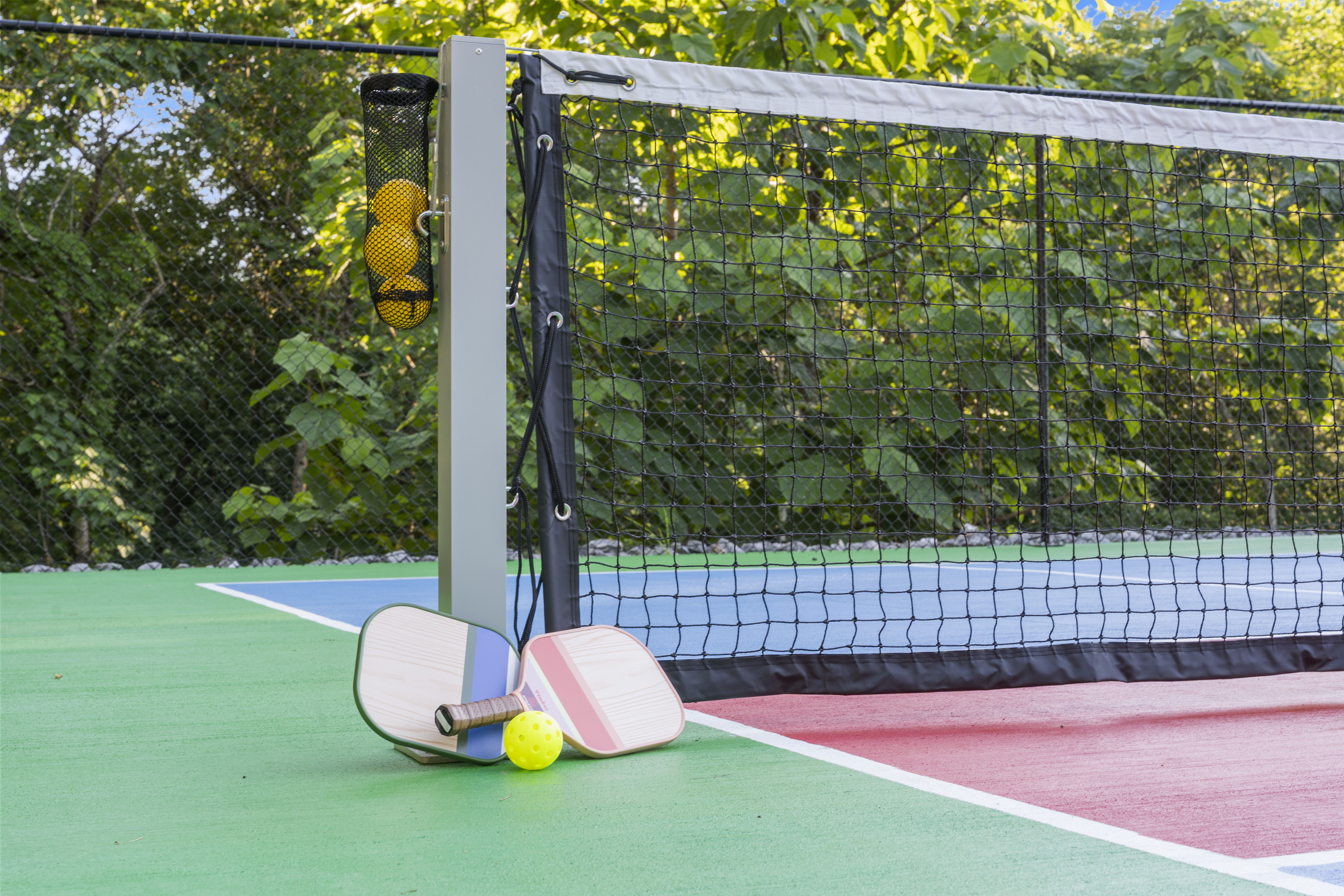 A pickleball net and paddles on the shared community court.